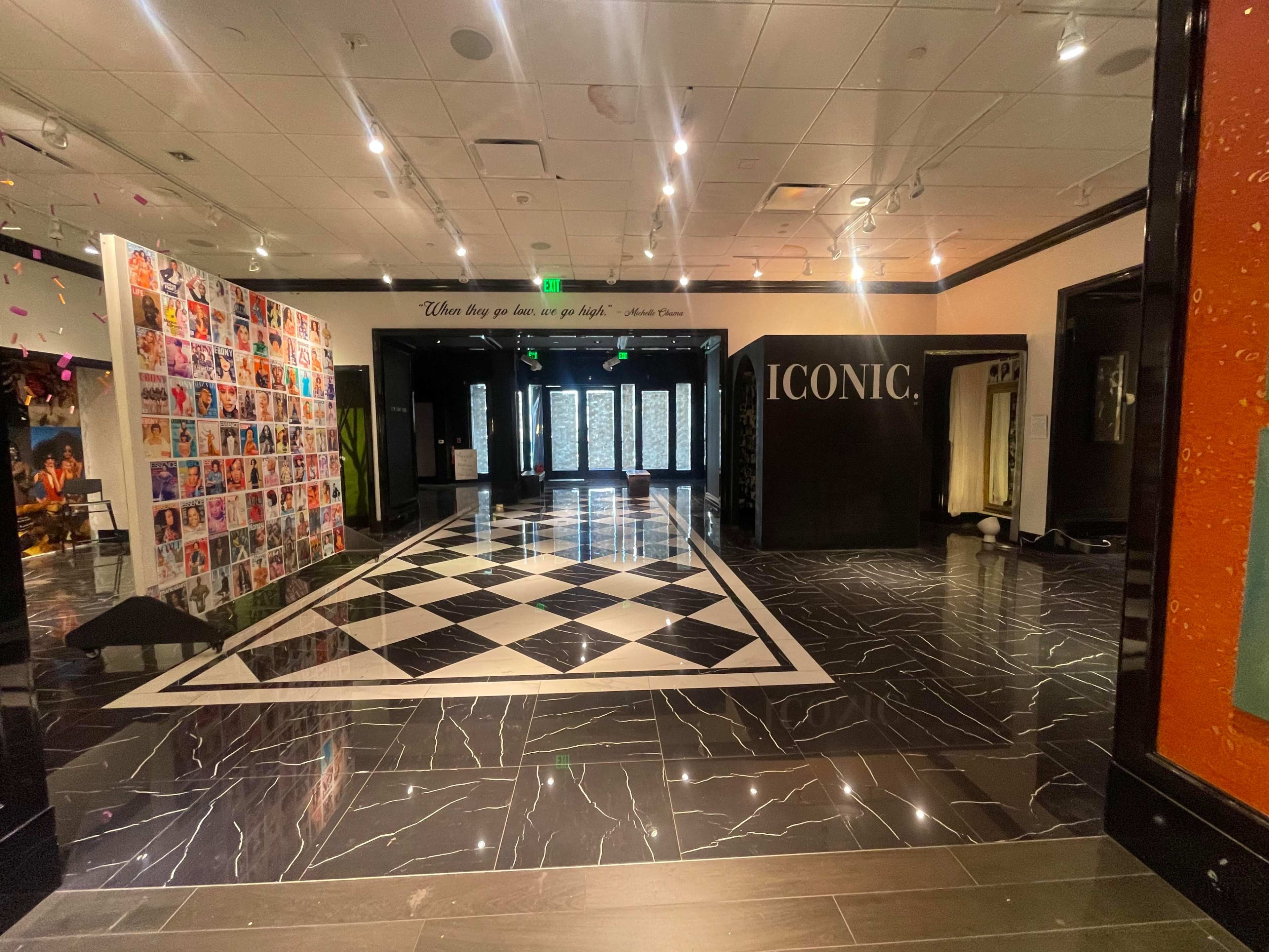 A spacious, modern interior with a black and white patterned floor, decorative walls featuring artwork, and a large "ICONIC" sign prominently displayed.