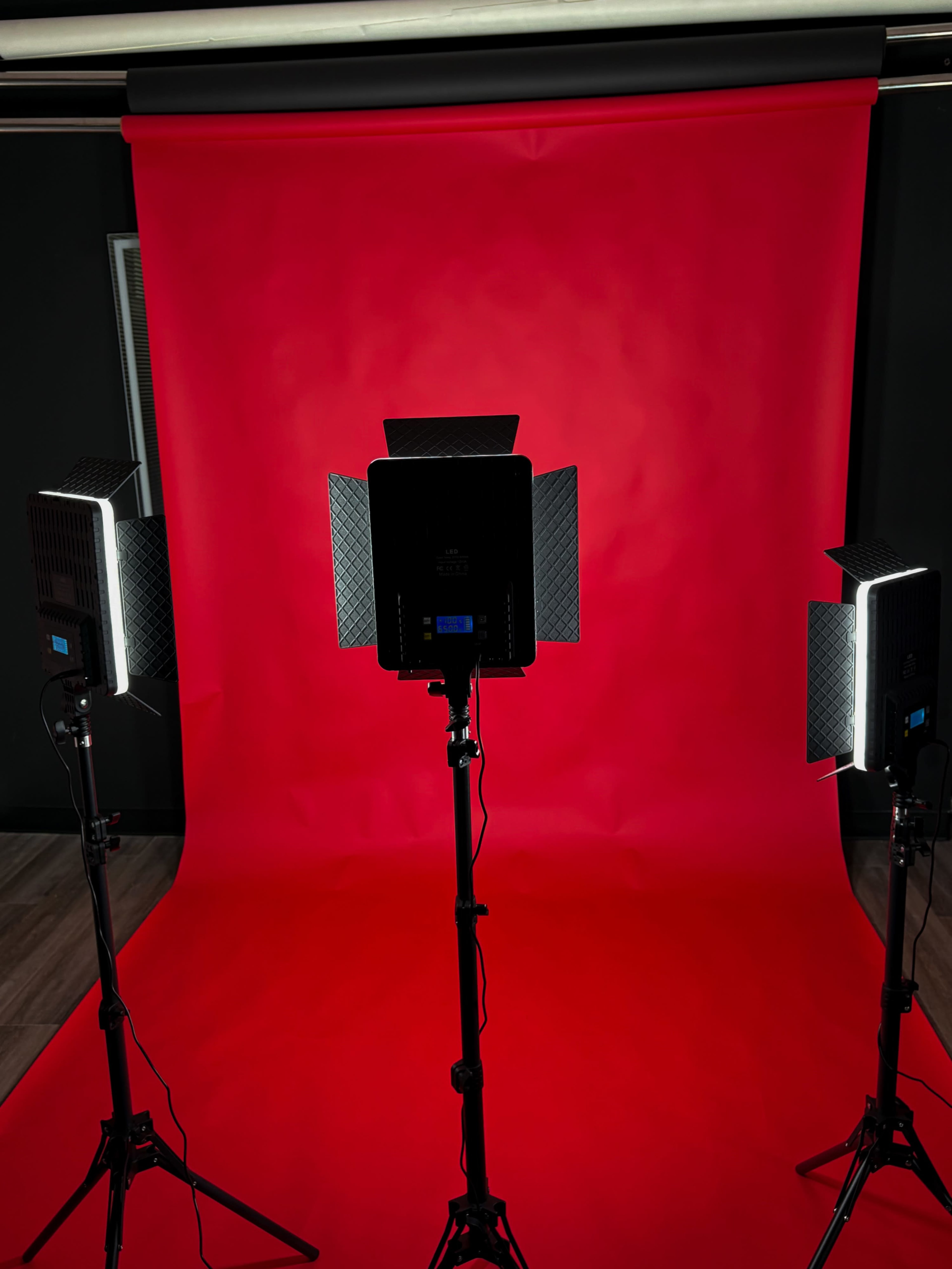 Two lighting setups are positioned in front of a bright red backdrop.