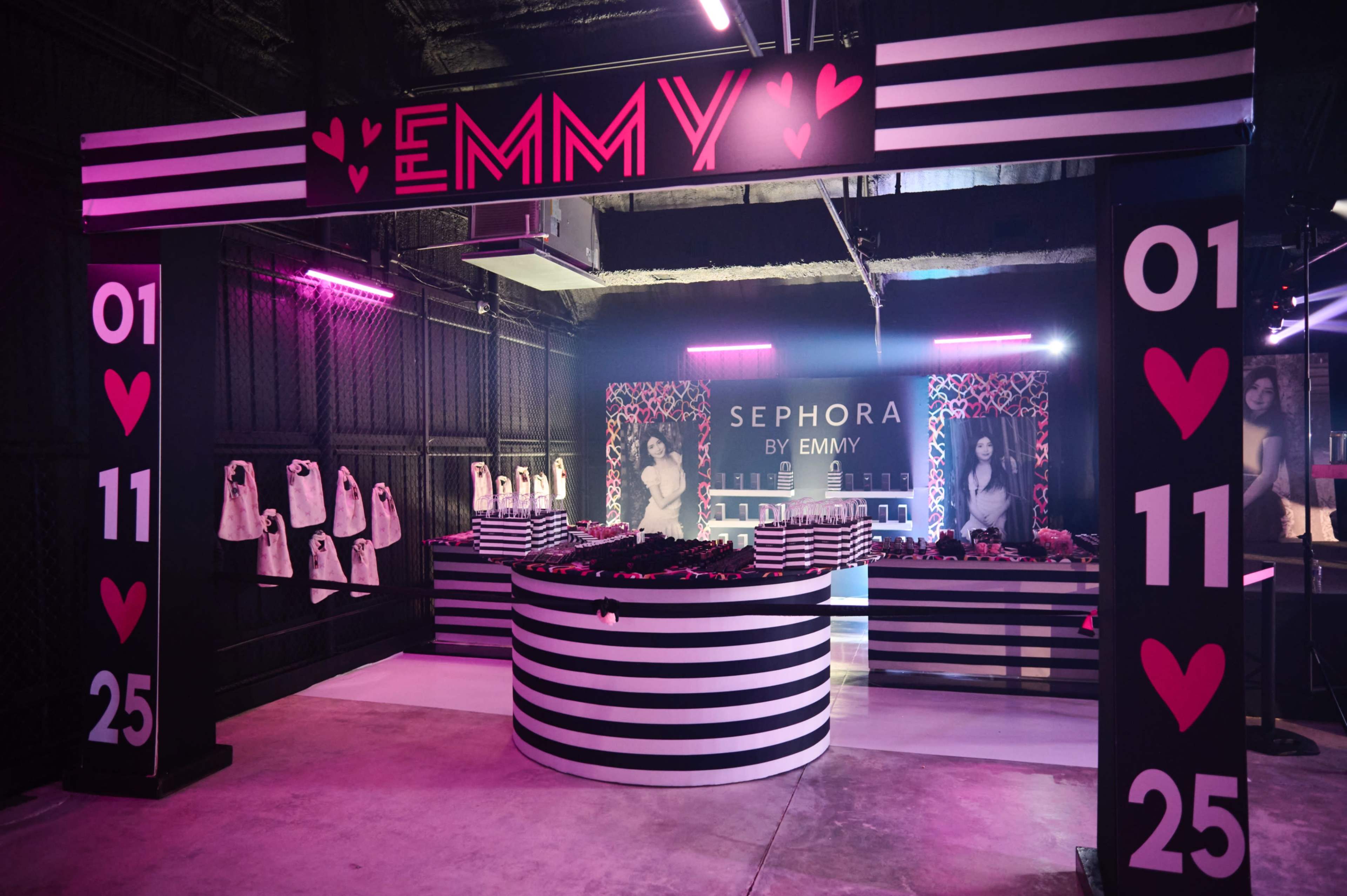The image shows a promotional event space featuring a black and white striped booth with the name "EMMY" prominently displayed, flanked by decorations and products from Sephora.