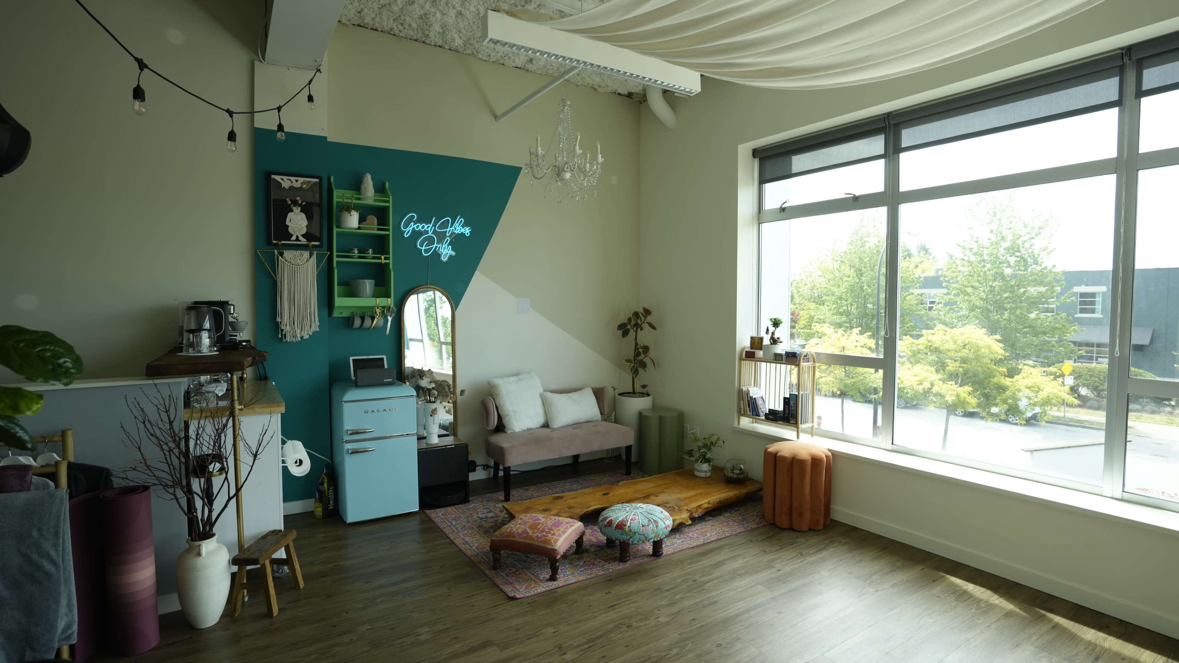 The interior features a cozy living space with a pink sofa, a blue accent wall, and large windows that let in natural light.