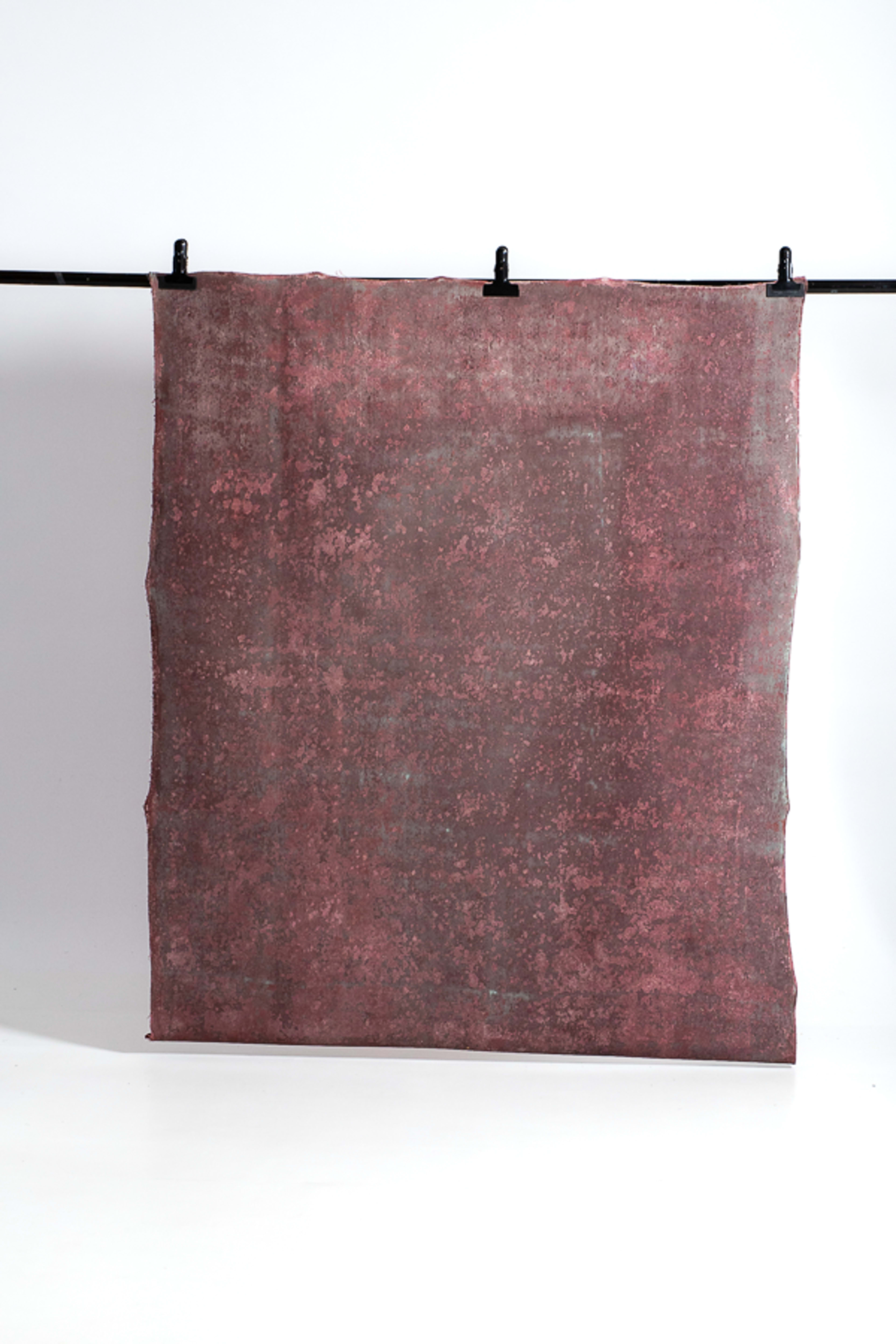 A textured fabric with a faded pink and gray pattern hangs from a black pole against a white background.