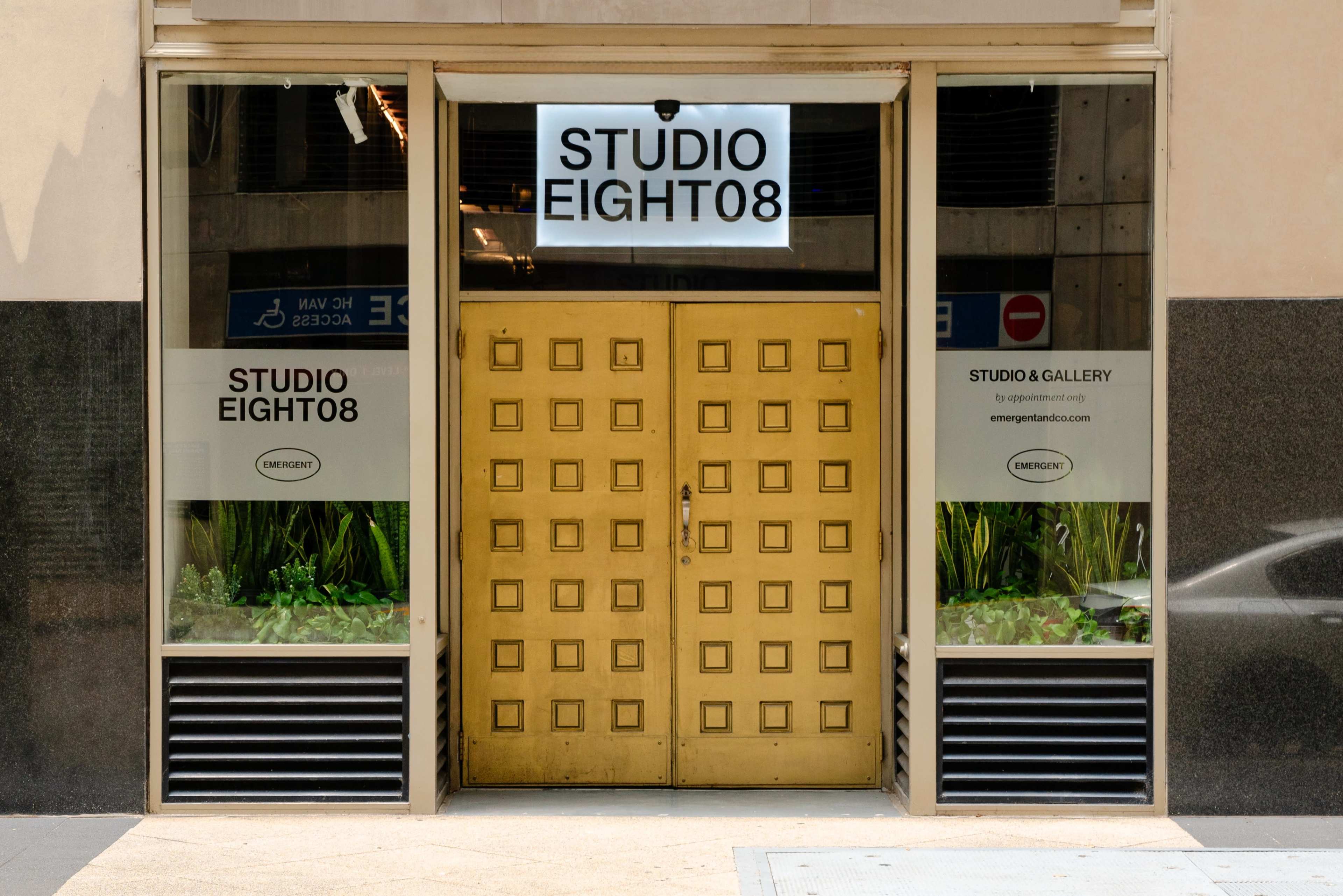 The image shows the entrance of a building with a set of large, golden double doors and windows marked with the name "STUDIO EIGHT08."