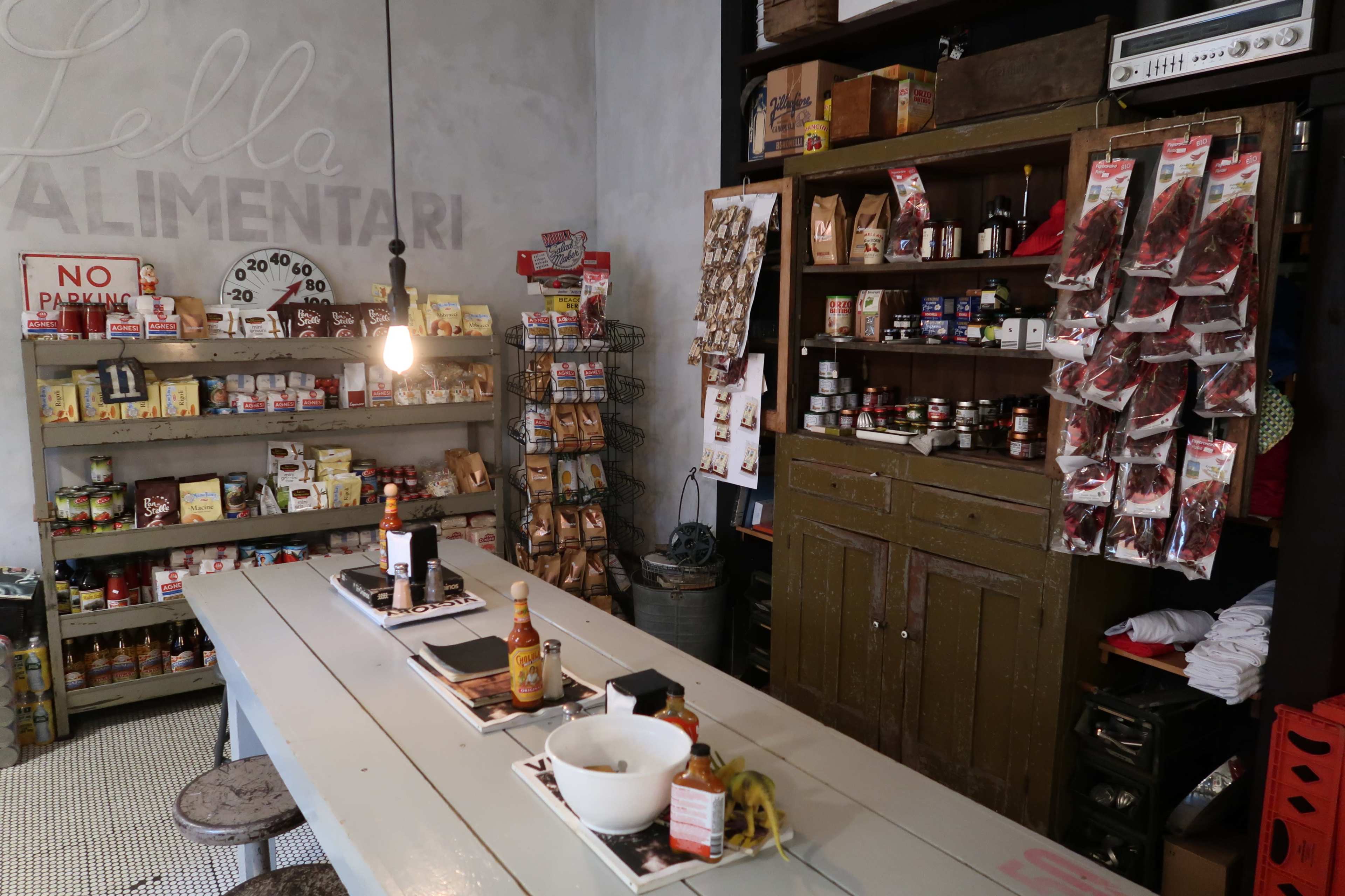A cozy shop interior filled with shelves of various packaged food items, jars, and snacks, with a rustic wooden counter in the foreground.