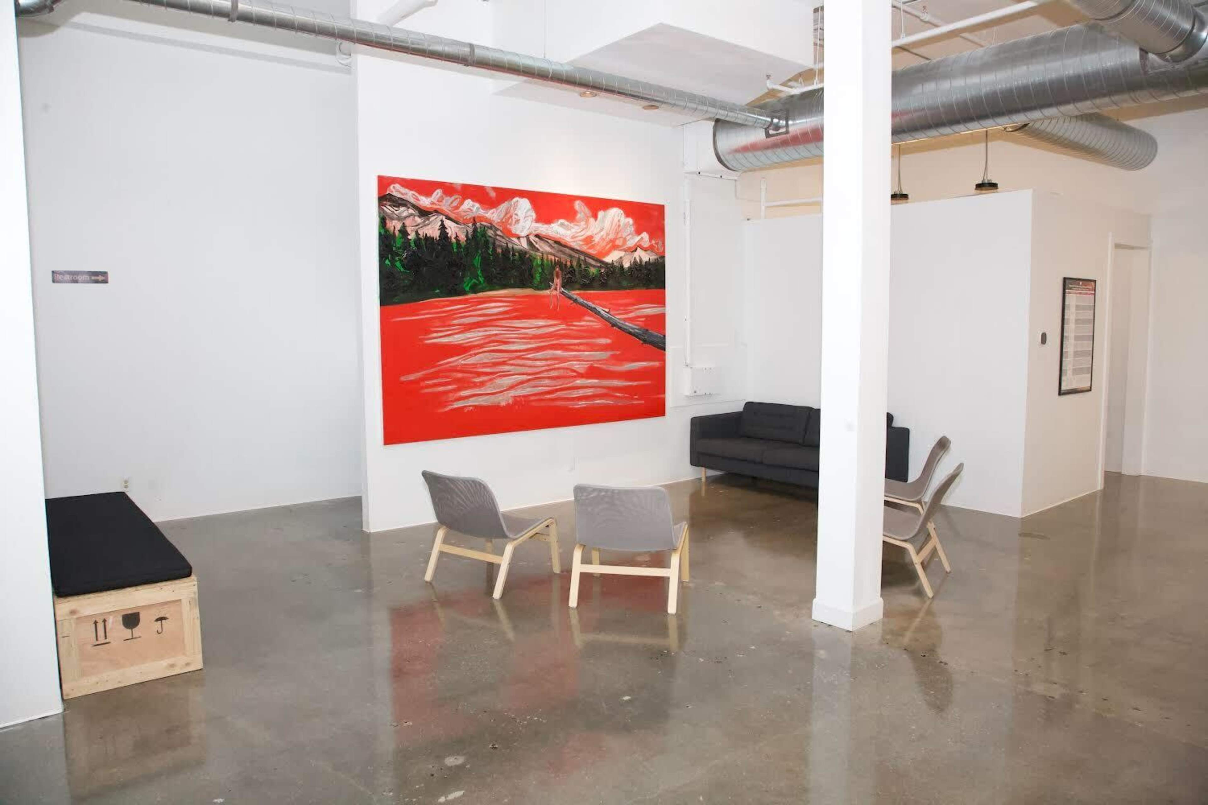The image shows a modern, minimalist interior space featuring a seating area with two chairs and a sofa, a large red landscape painting on one wall, and polished concrete floors.