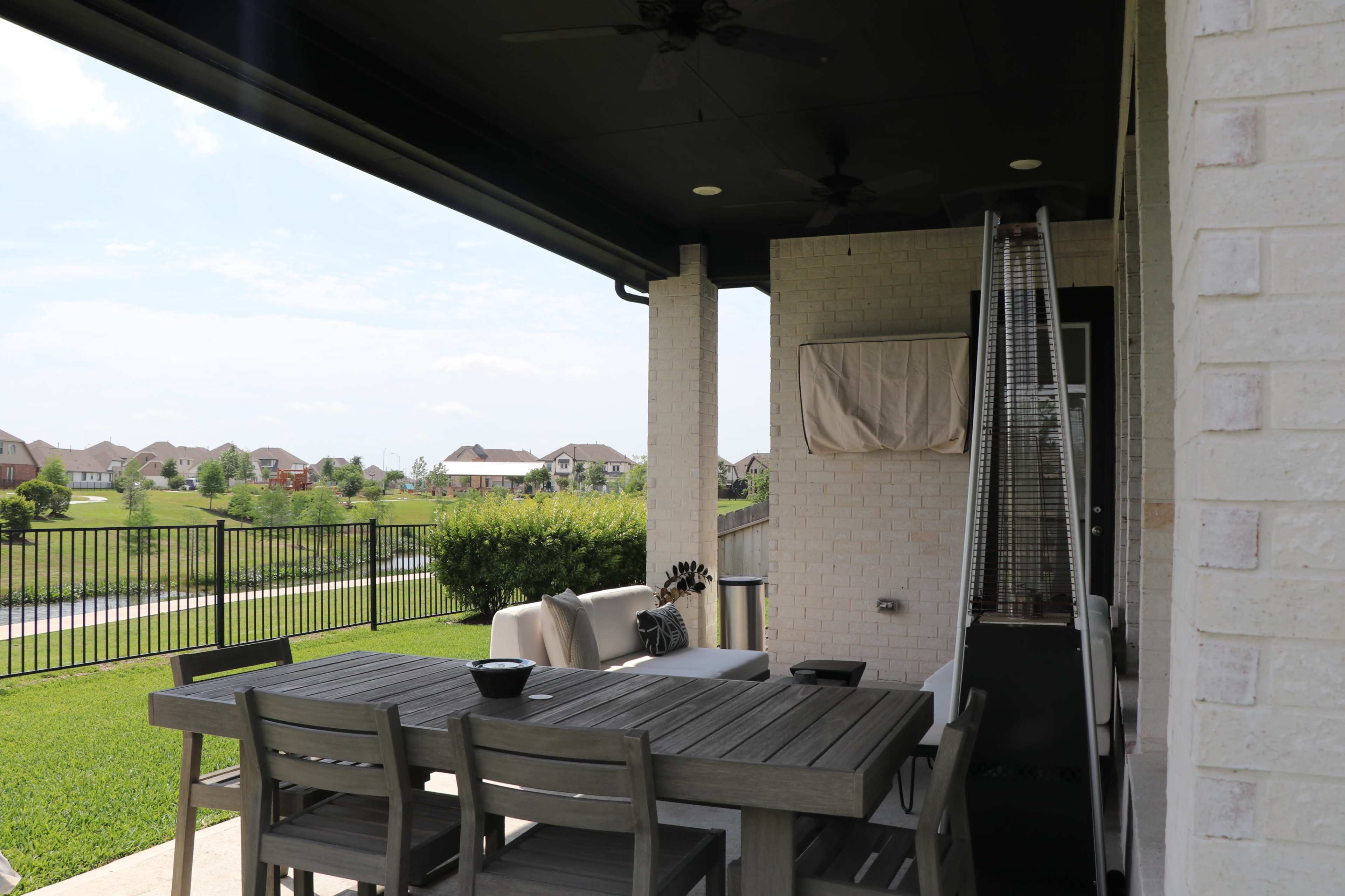A patio with a dining table and chairs overlooks a grassy area and houses in the distance.