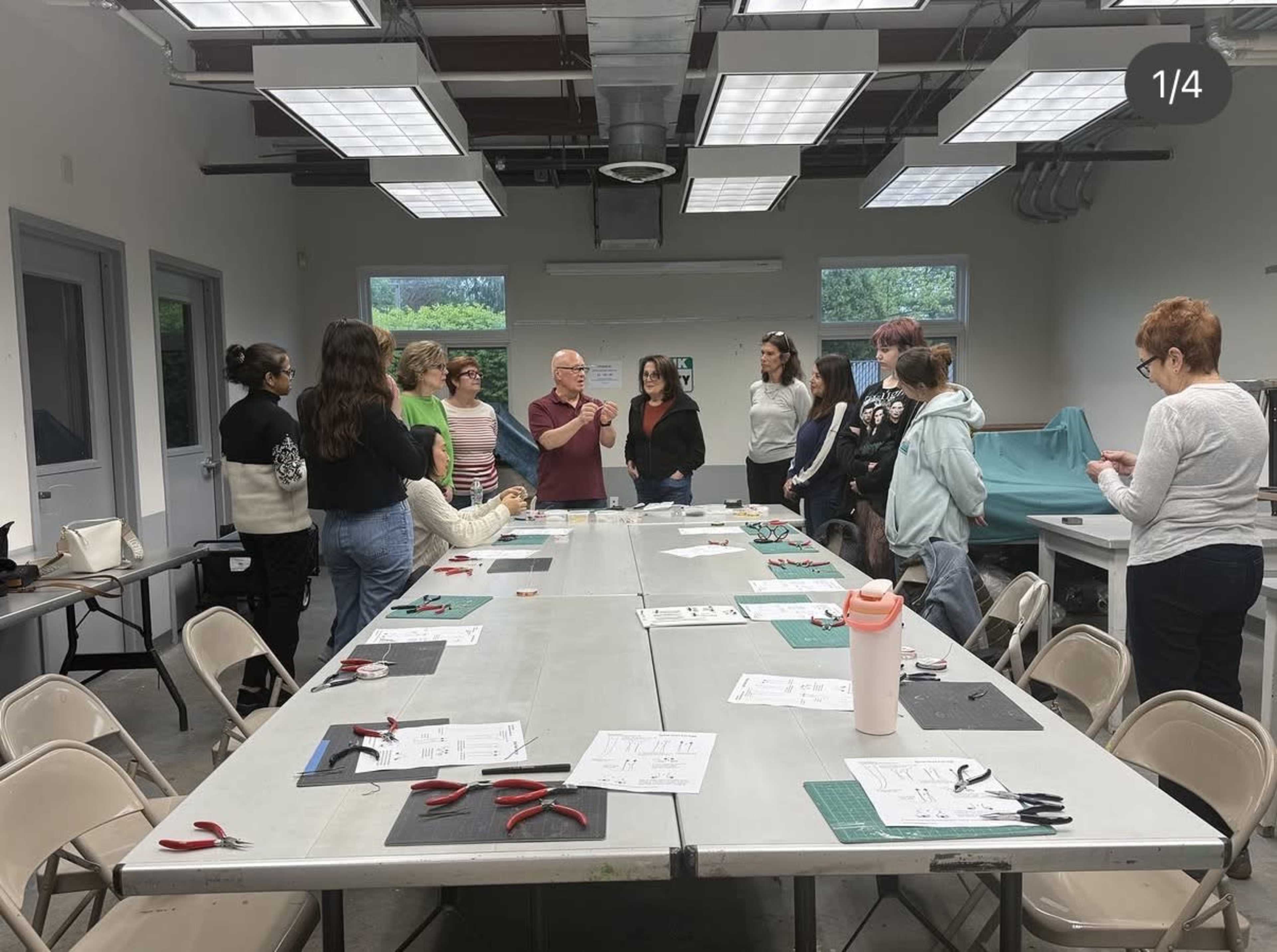 A group of people gathers around a table in a classroom, where an instructor appears to be demonstrating a technique.