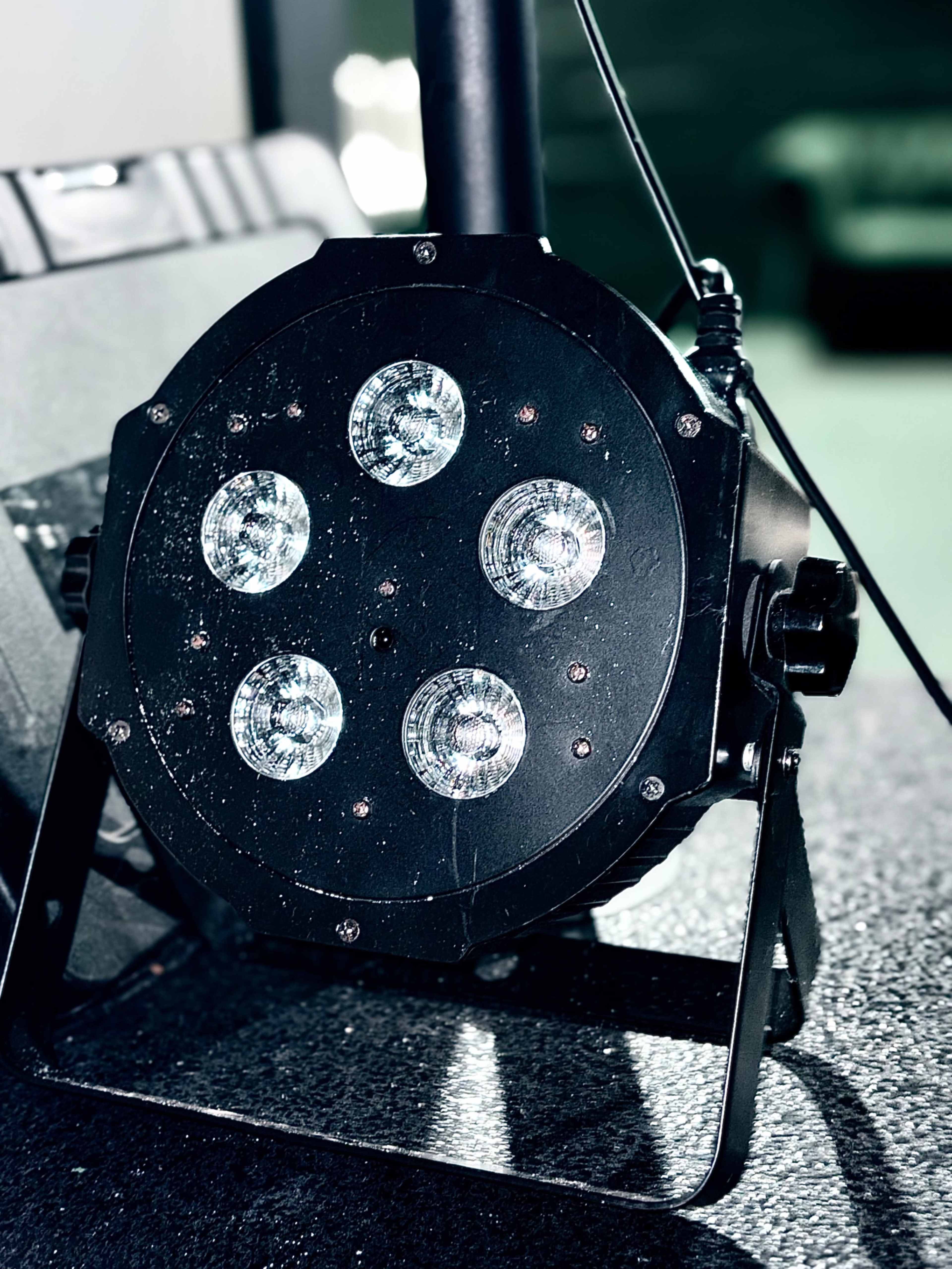 A black stage light with five circular LED bulbs is positioned on a stand.