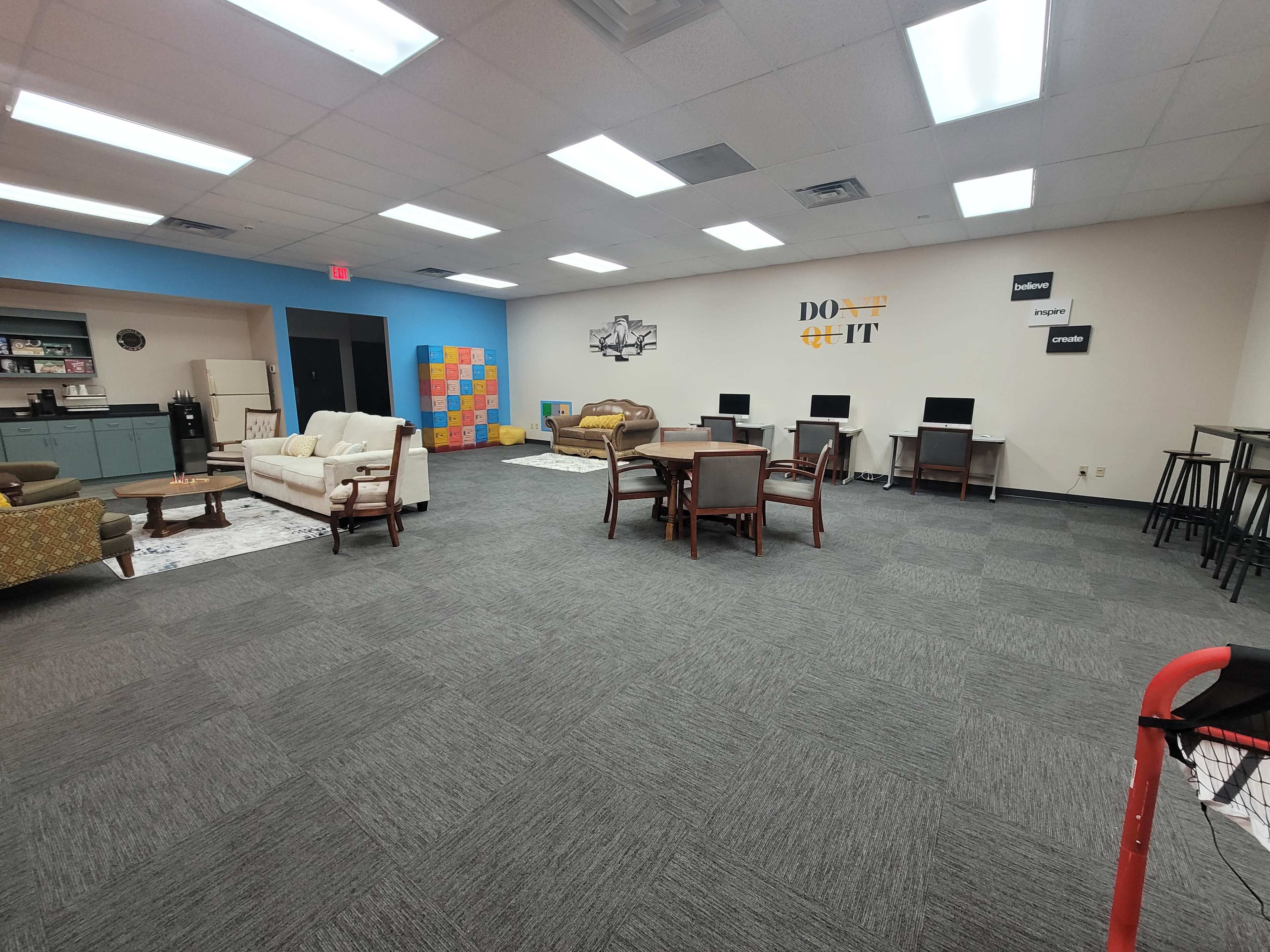 A spacious, well-lit common area featuring various seating arrangements, computer stations, and colorful wall decor.