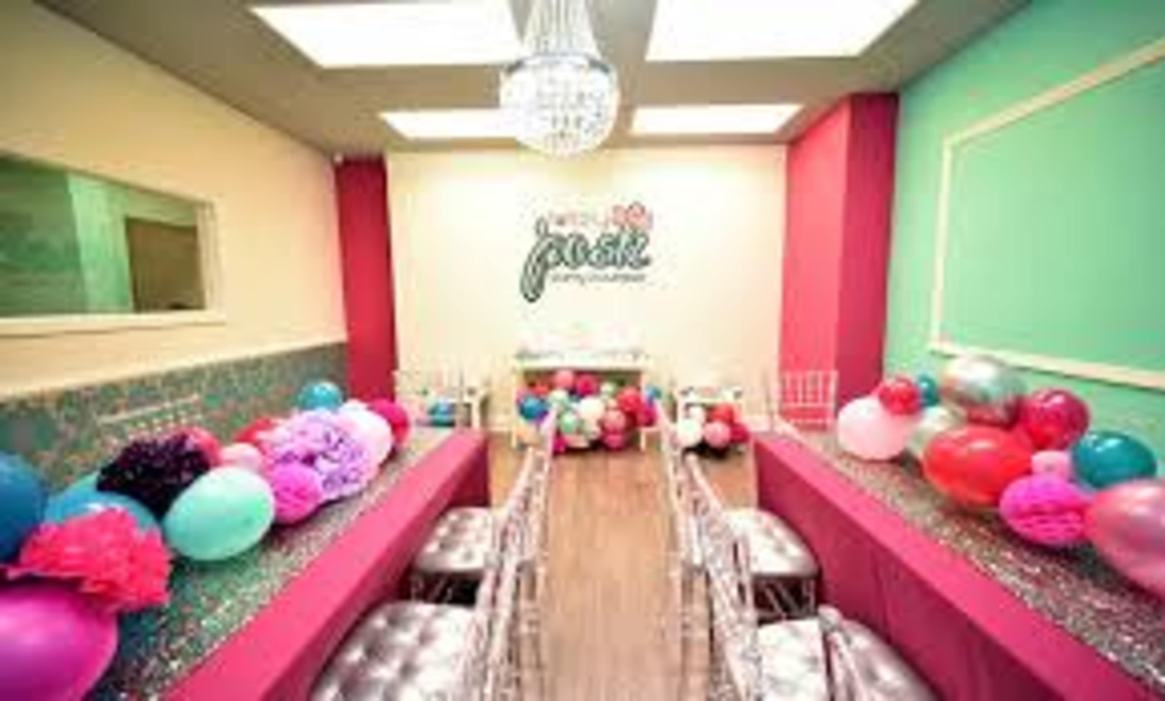A colorful party room decorated with balloons and a sparkling table set for an event.