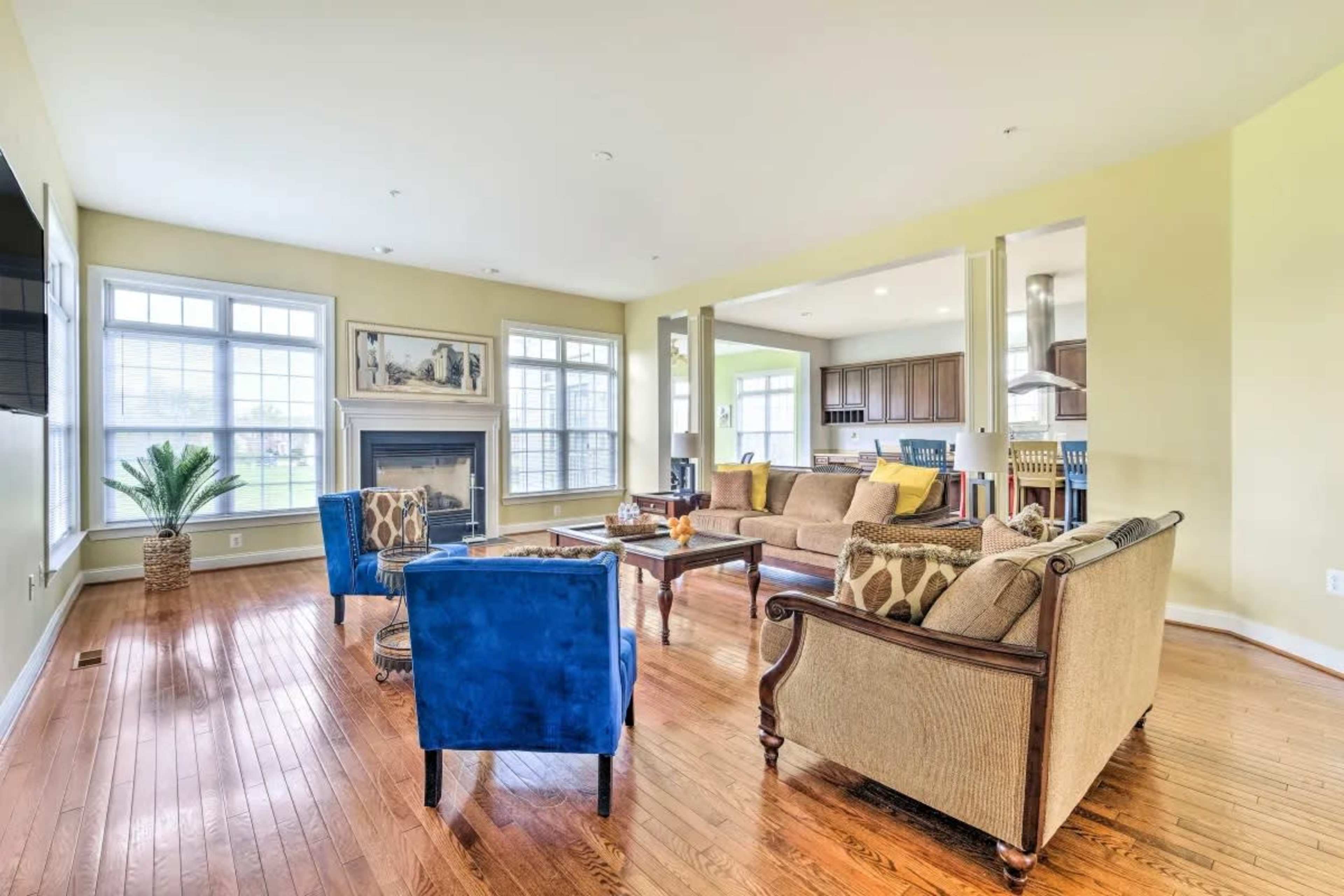 A spacious living room featuring a fireplace, a large window with natural light, and a combination of blue and tan seating arrangements.
