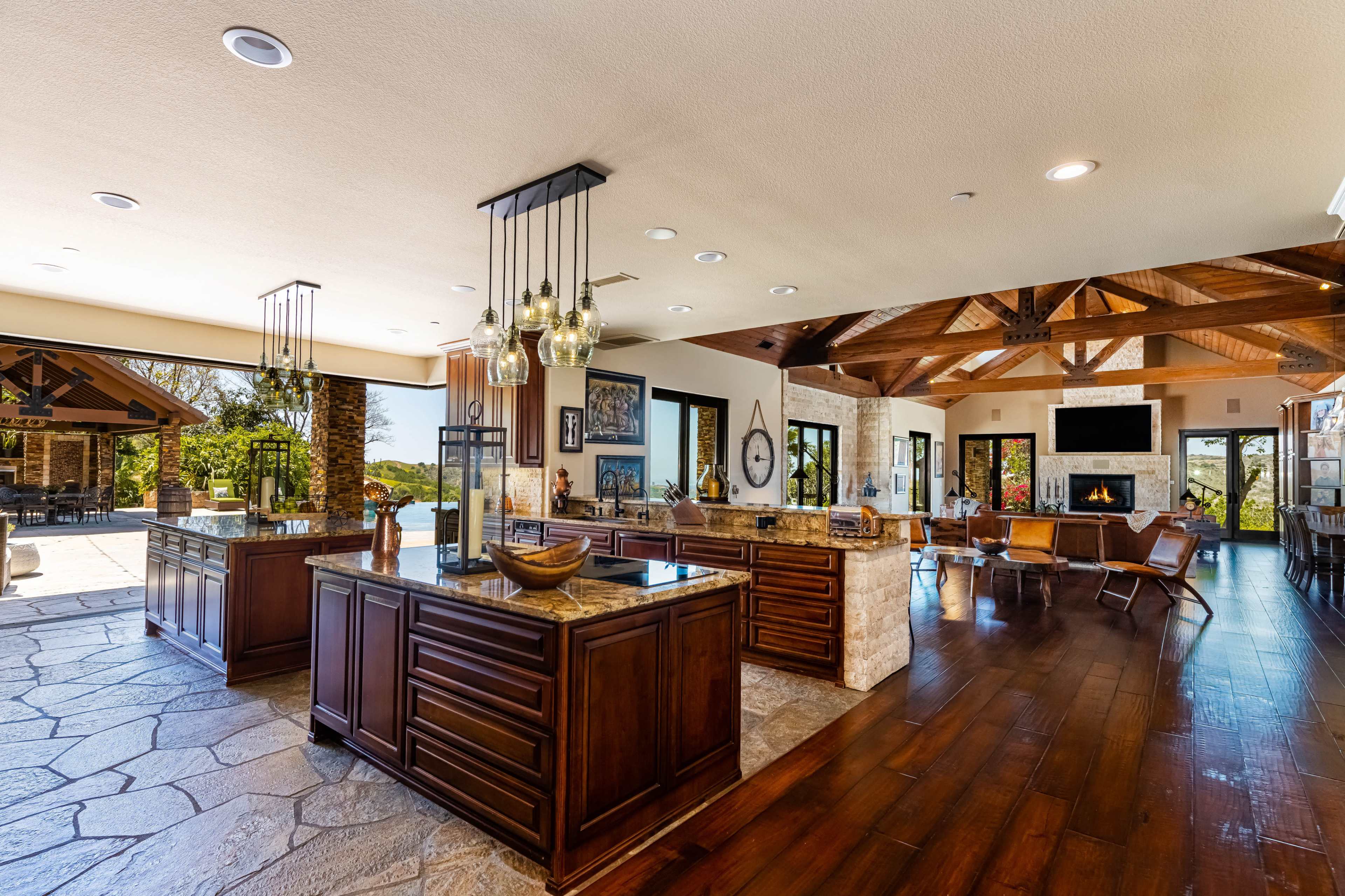 The spacious kitchen features dark wooden cabinets, granite countertops, and large windows that provide a view of the outdoor area.