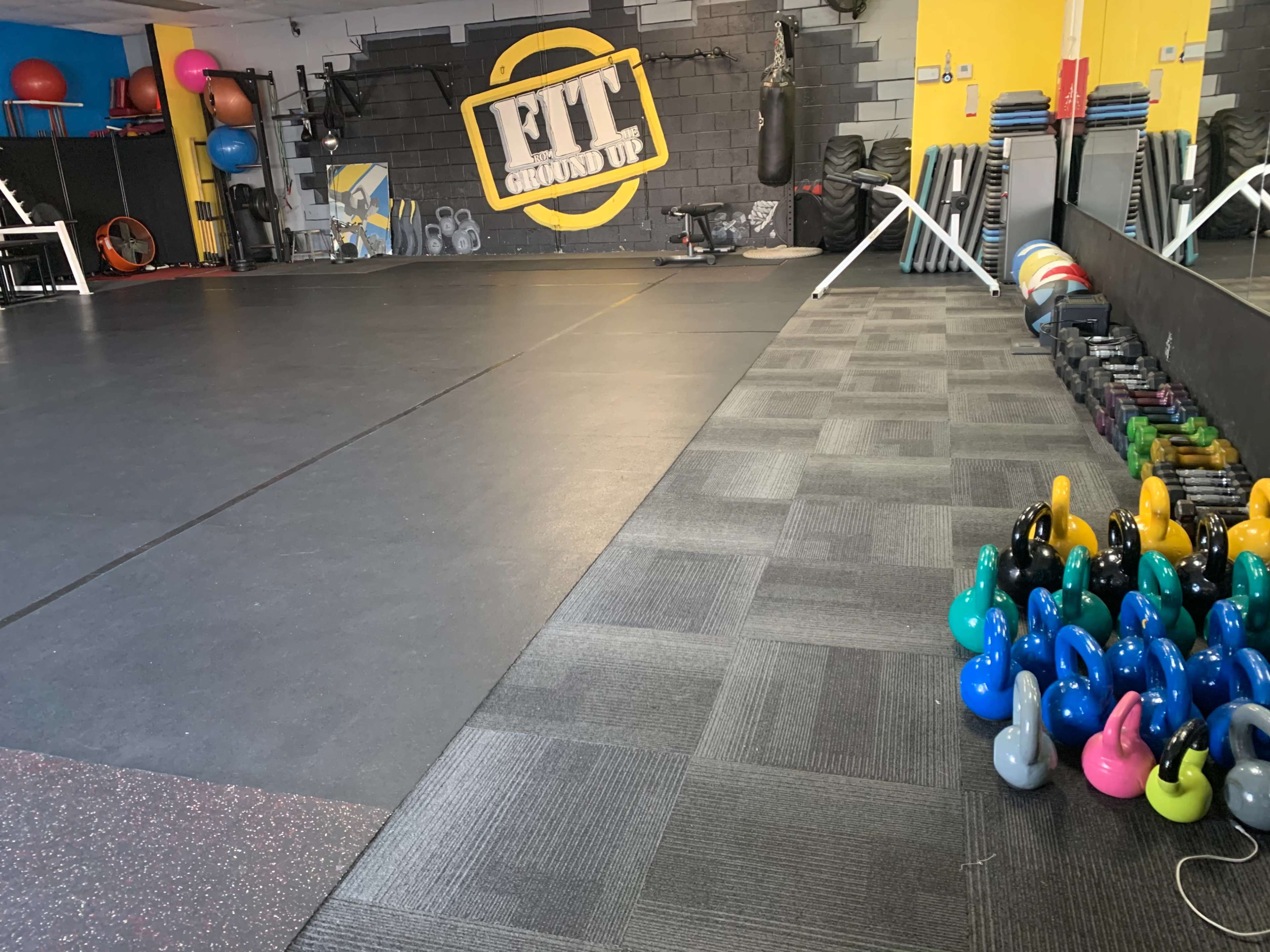 A fitness studio featuring exercise equipment, including kettlebells arranged on the floor and various fitness tools along the walls.