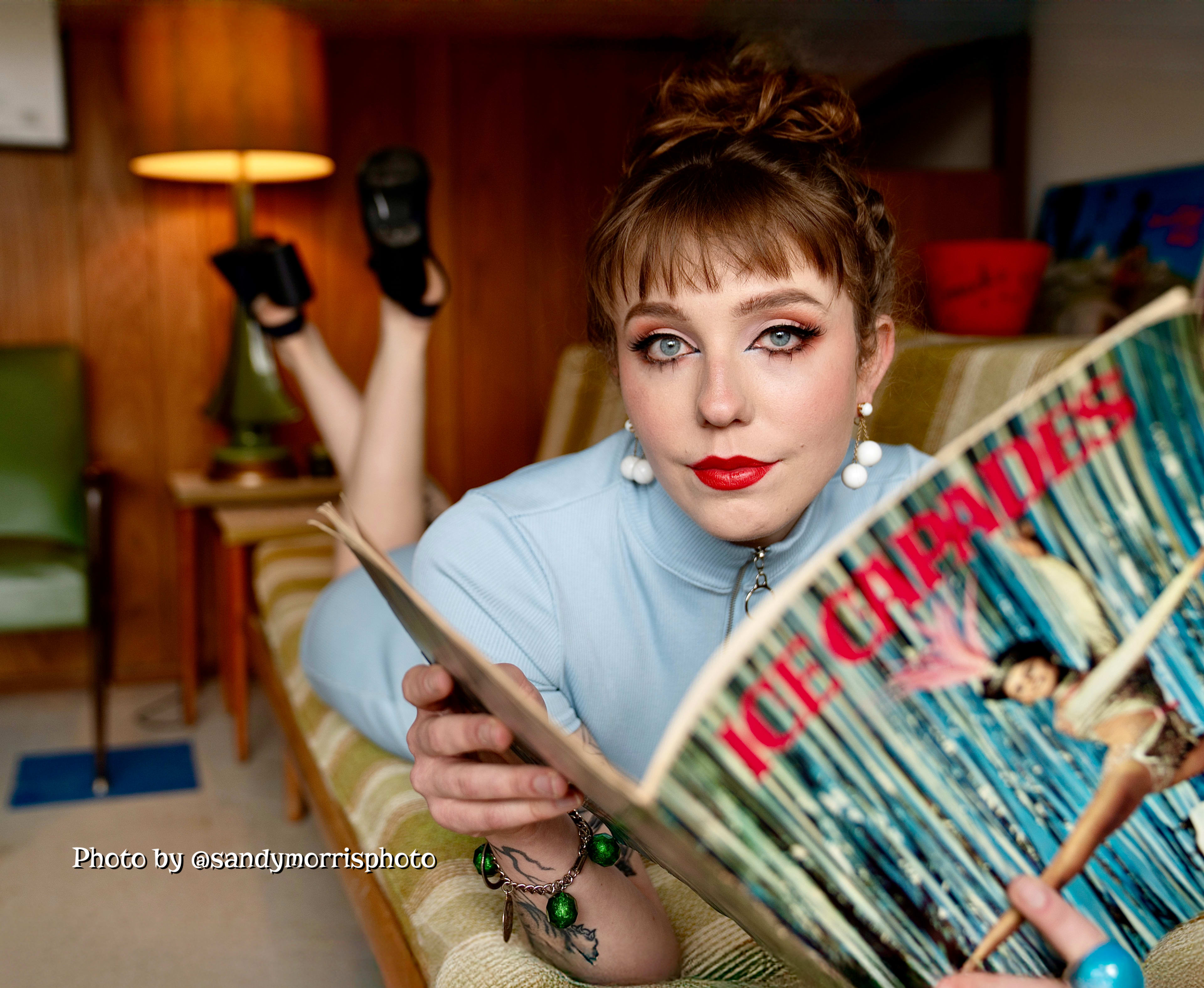A woman in a blue dress poses on a couch while reading a magazine titled "Ice Creams."