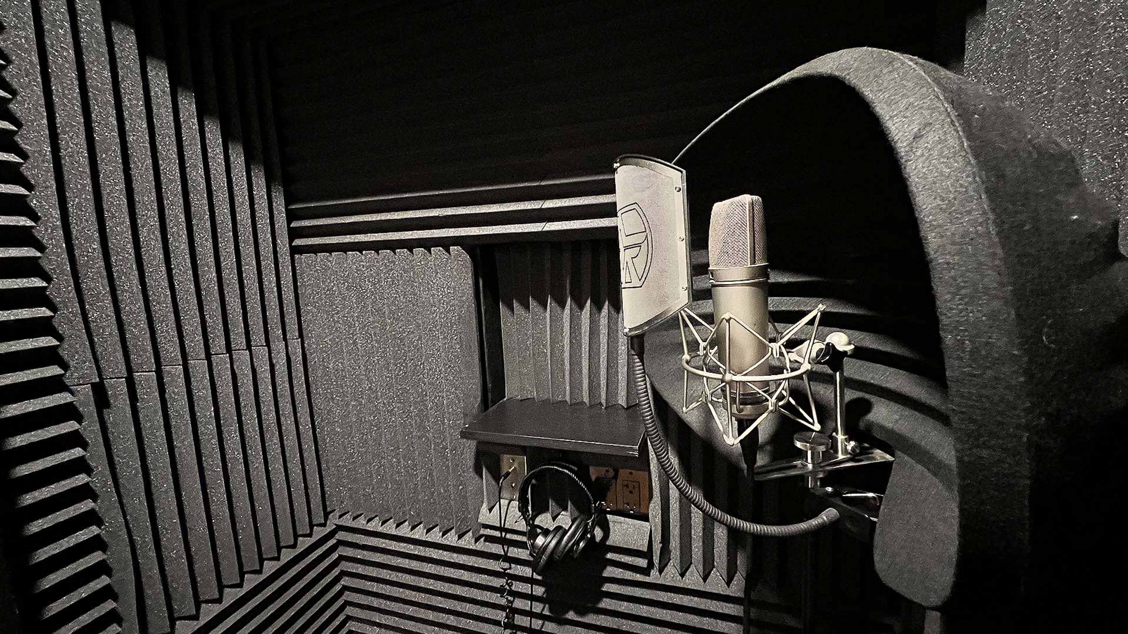 A soundproof recording booth equipped with a microphone and headphones.