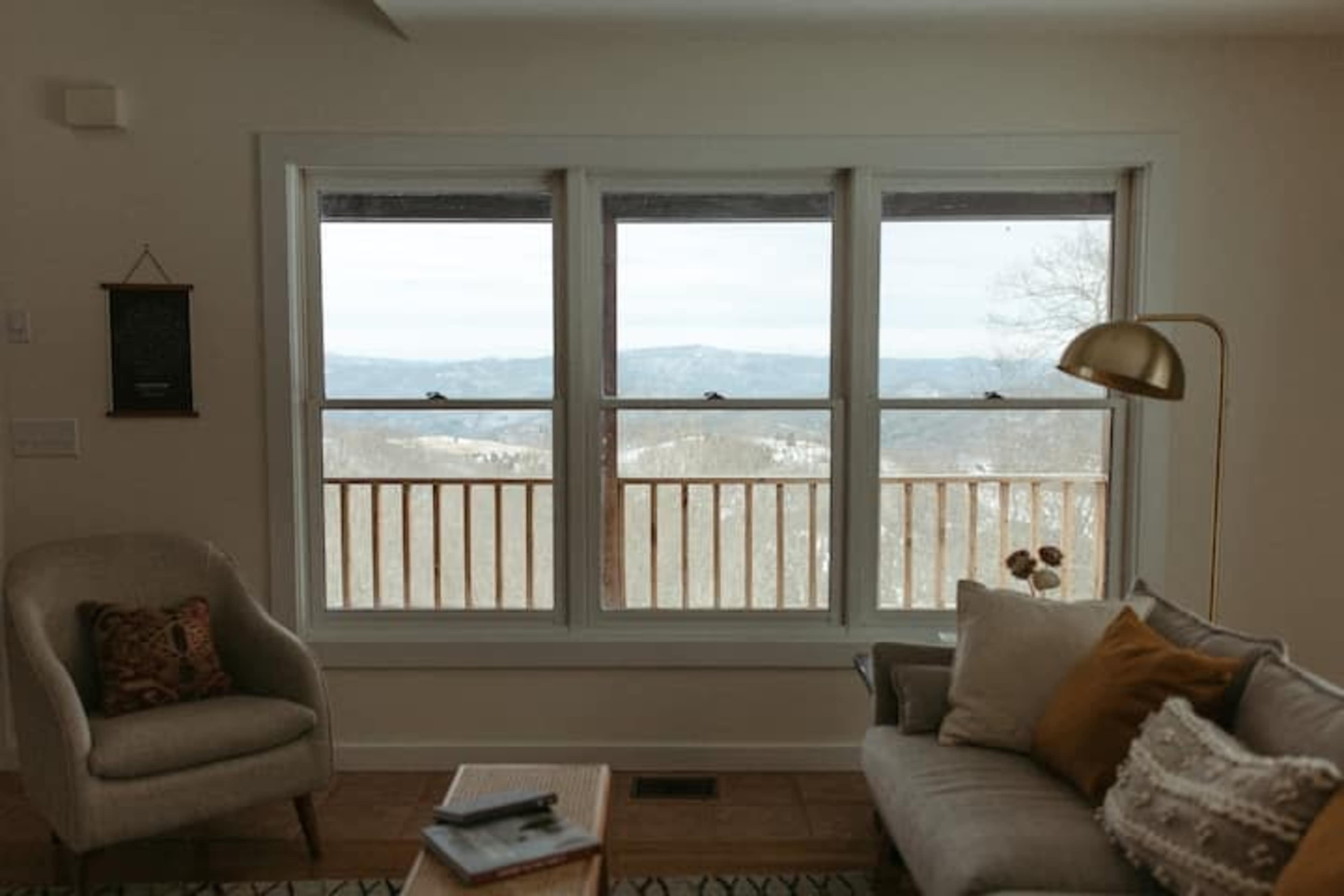 A cozy living room with a large window overlooking a scenic view of mountains and a valley.