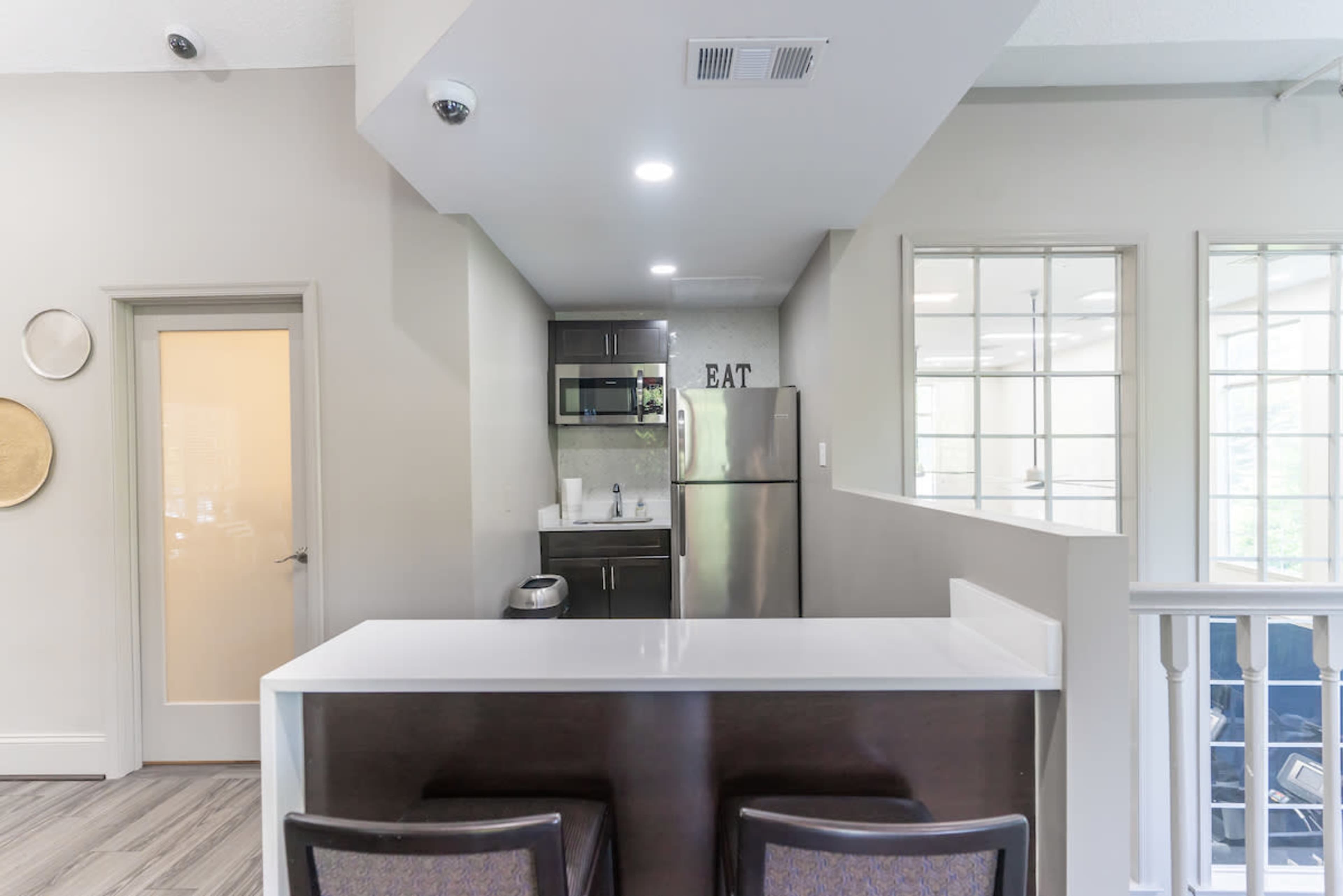 A modern kitchen features a white countertop with bar seating and stainless steel appliances.