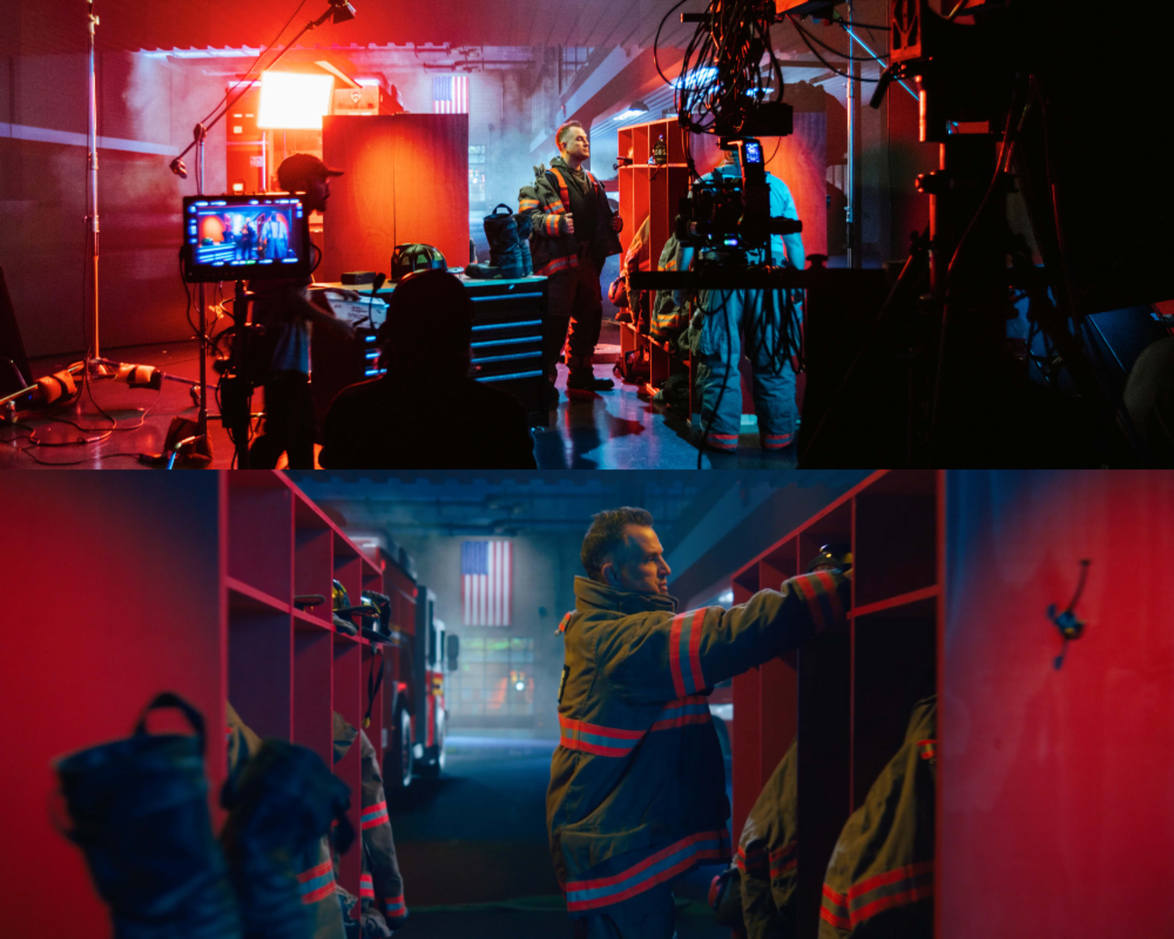 A film set featuring a fire department scene, with crew members preparing equipment and a firefighter interacting with fire gear in a dimly lit environment.
