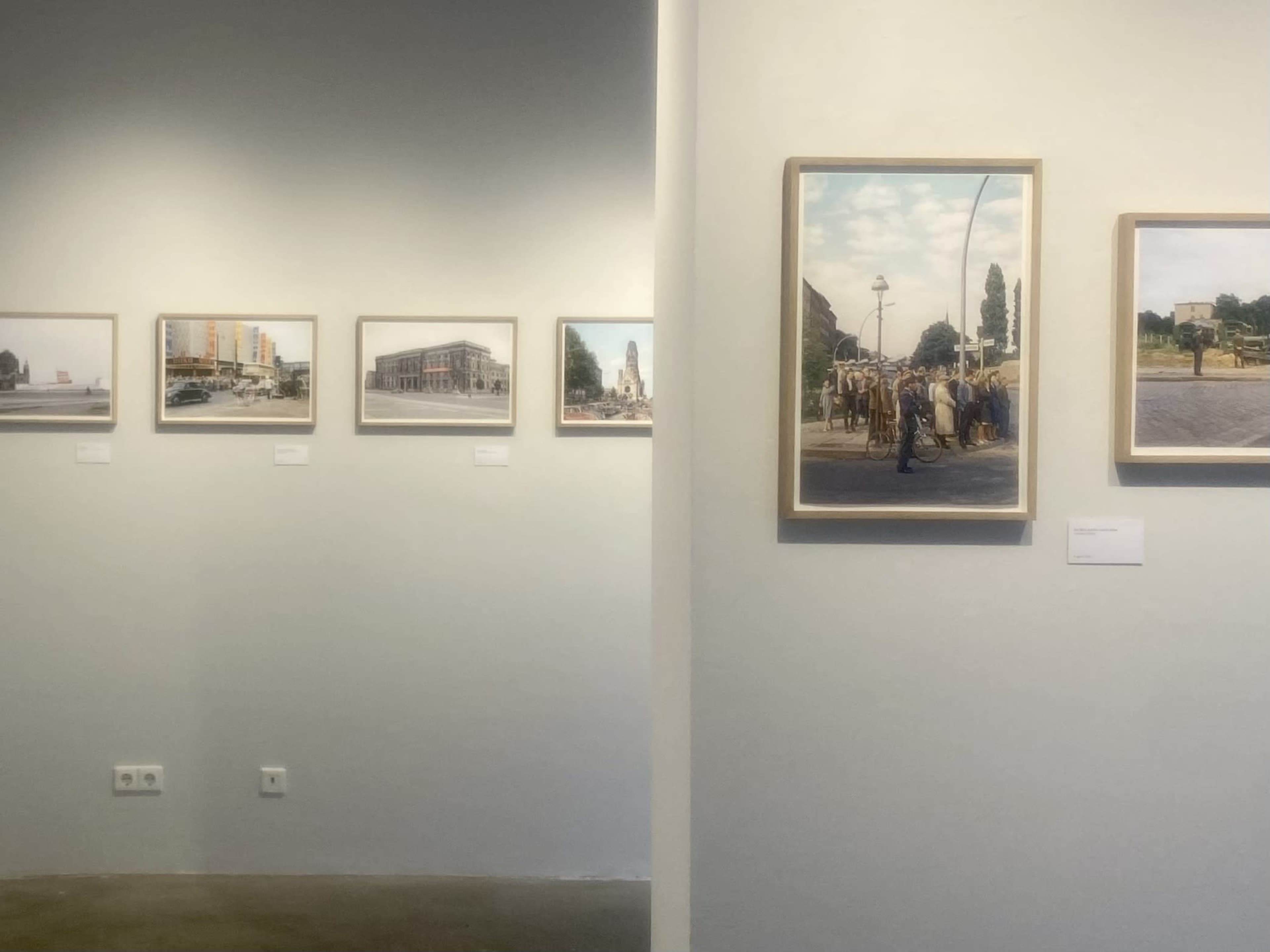 The image shows an art gallery with framed photographs displayed on the walls, showcasing various urban scenes.