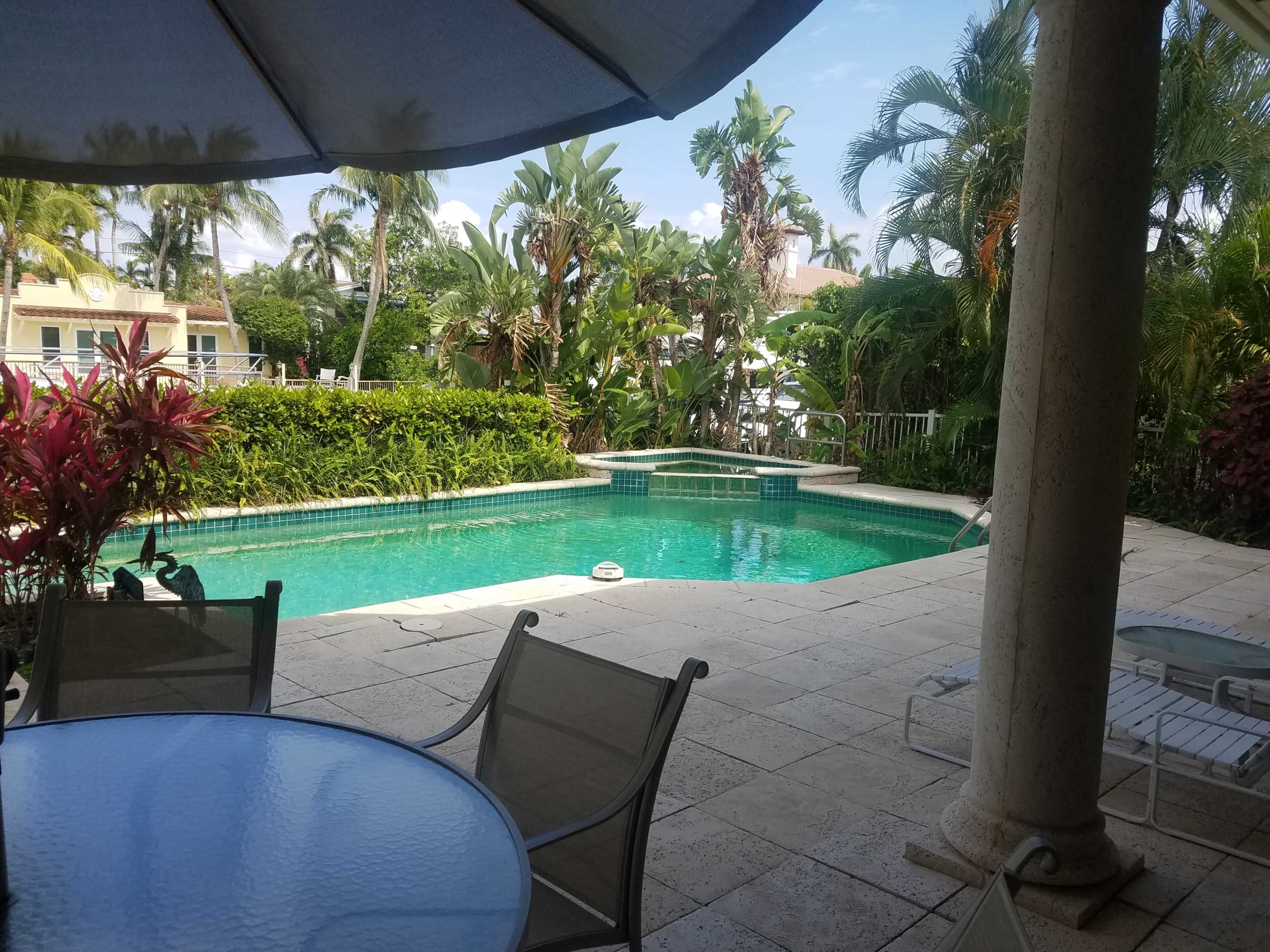 A swimming pool surrounded by lush tropical vegetation and a patio area with outdoor seating.