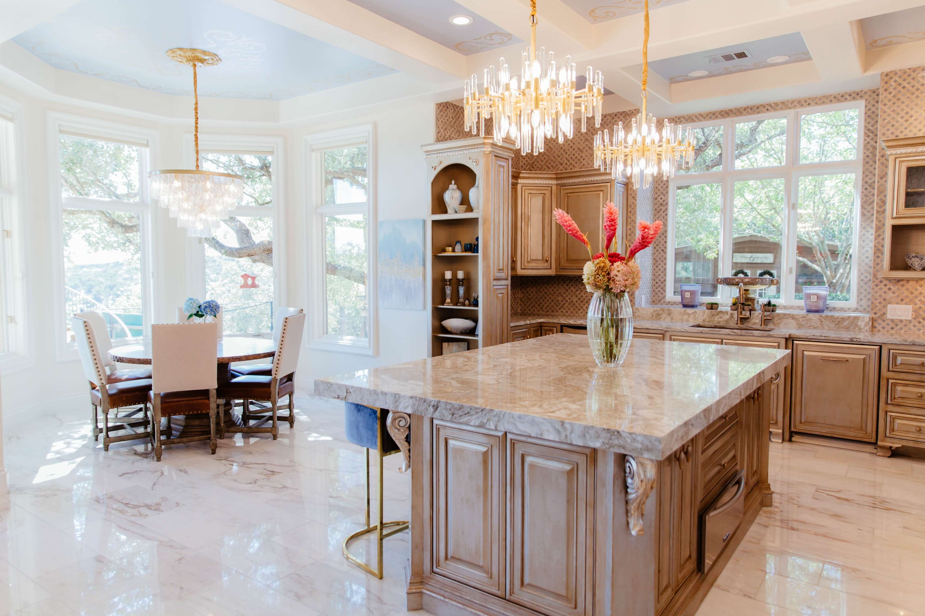 A spacious kitchen with a large island, wooden cabinetry, and a dining area featuring a round table surrounded by upholstered chairs.