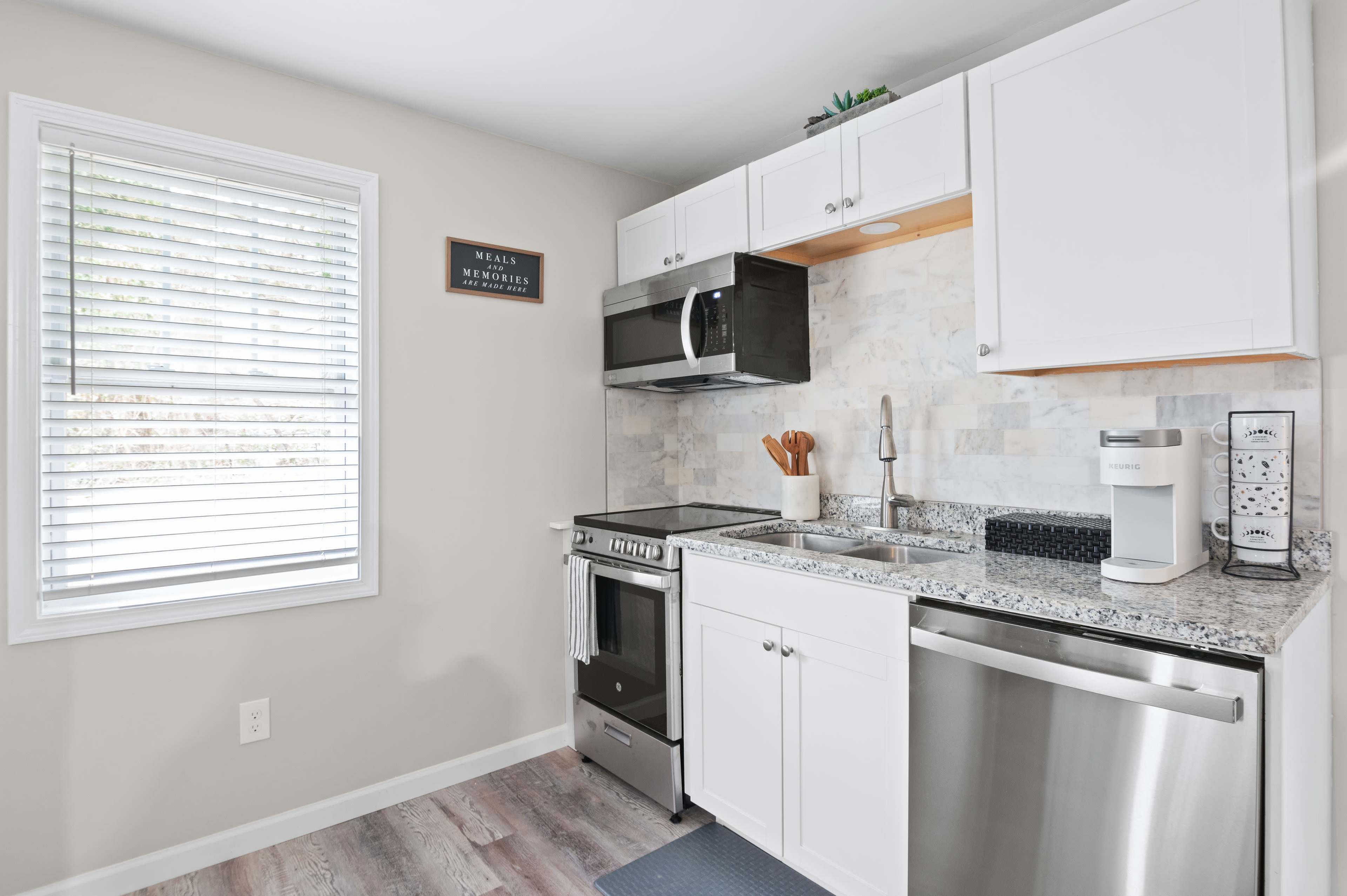 The image shows a modern kitchen featuring white cabinets, a stainless steel stove, and a countertop with a speckled design.