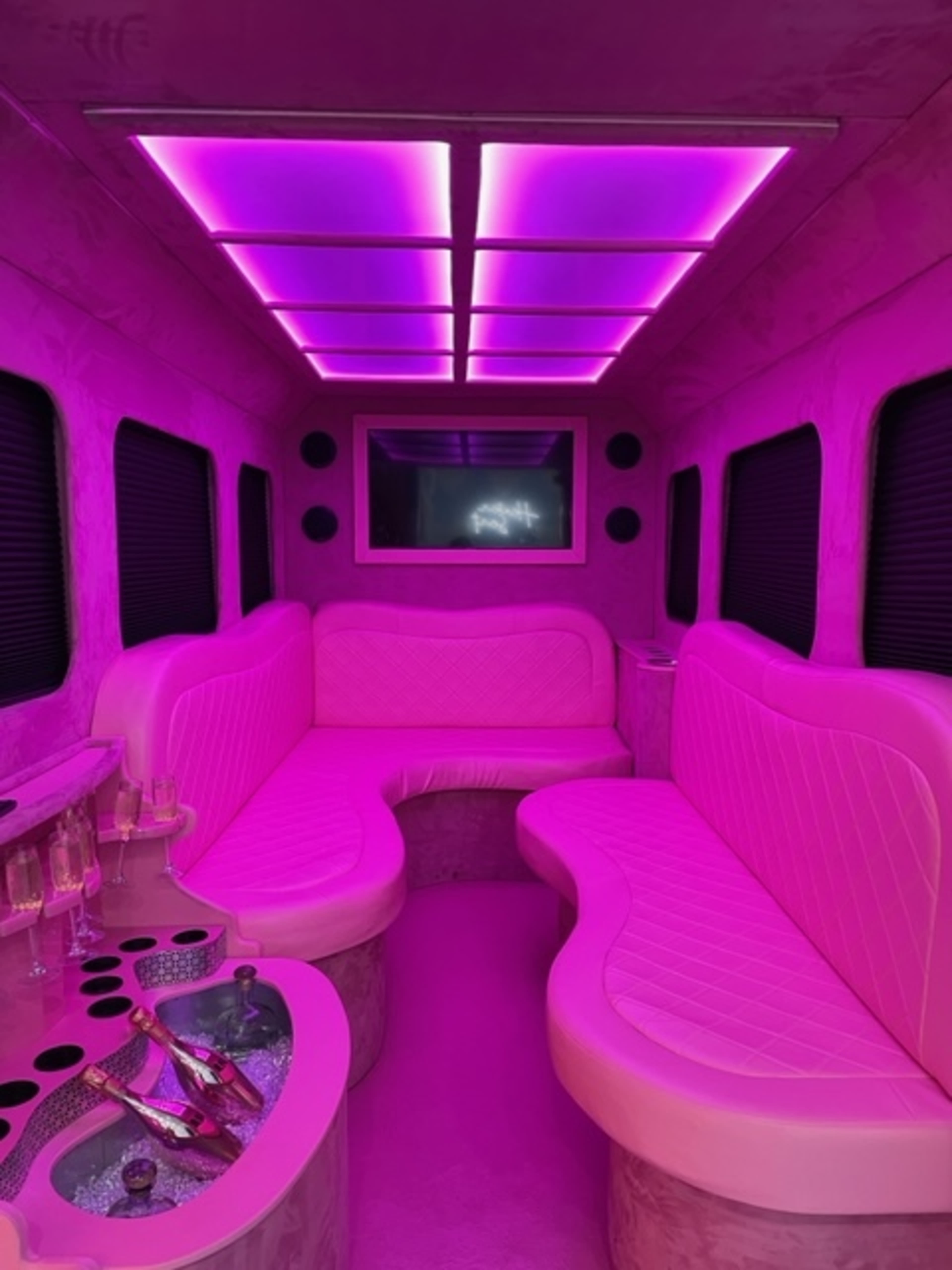 The interior of a limousine features curved seating and purple LED lighting.