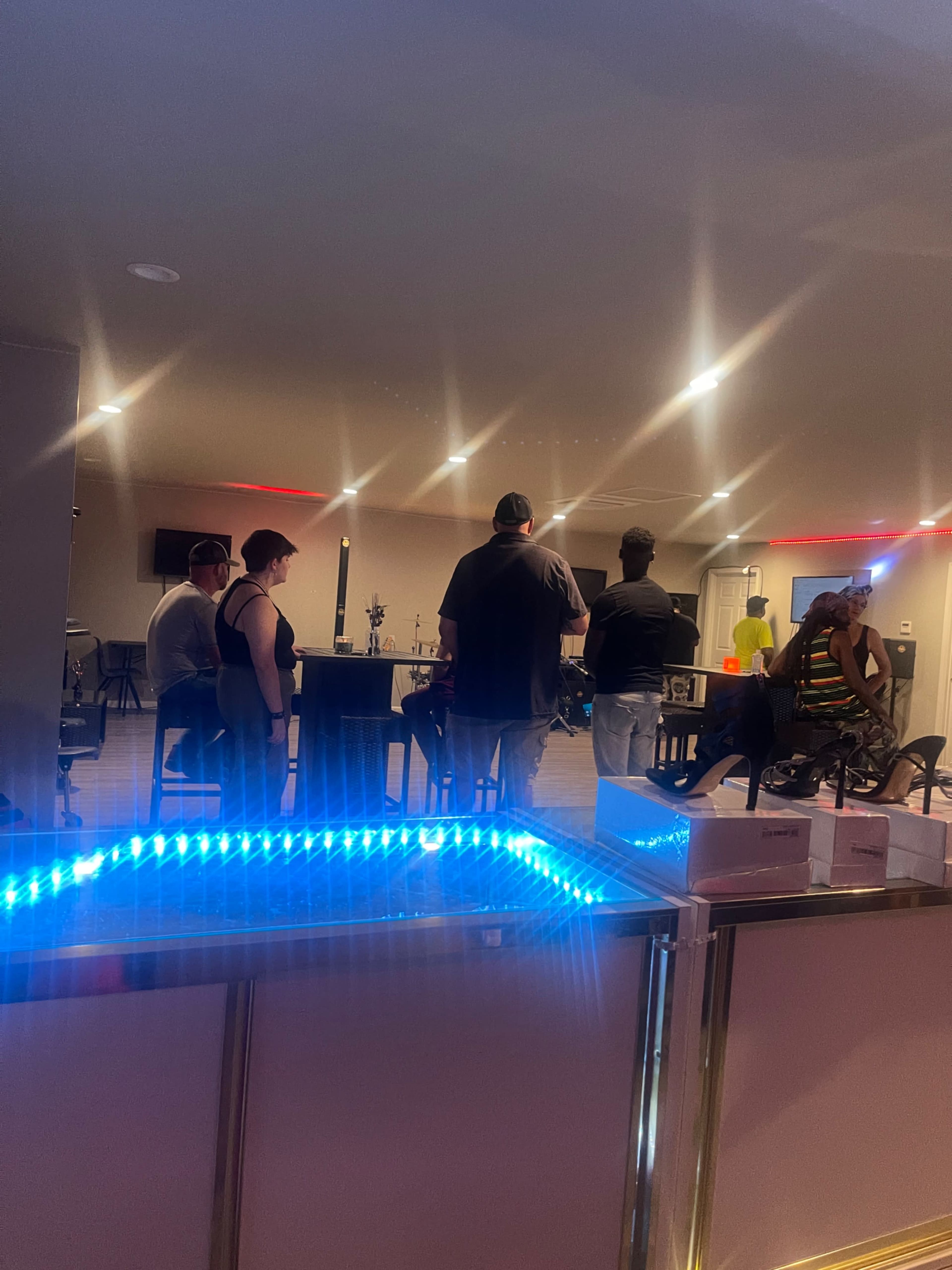 A group of five people stands in a well-lit room with a modern bar area and various tables.