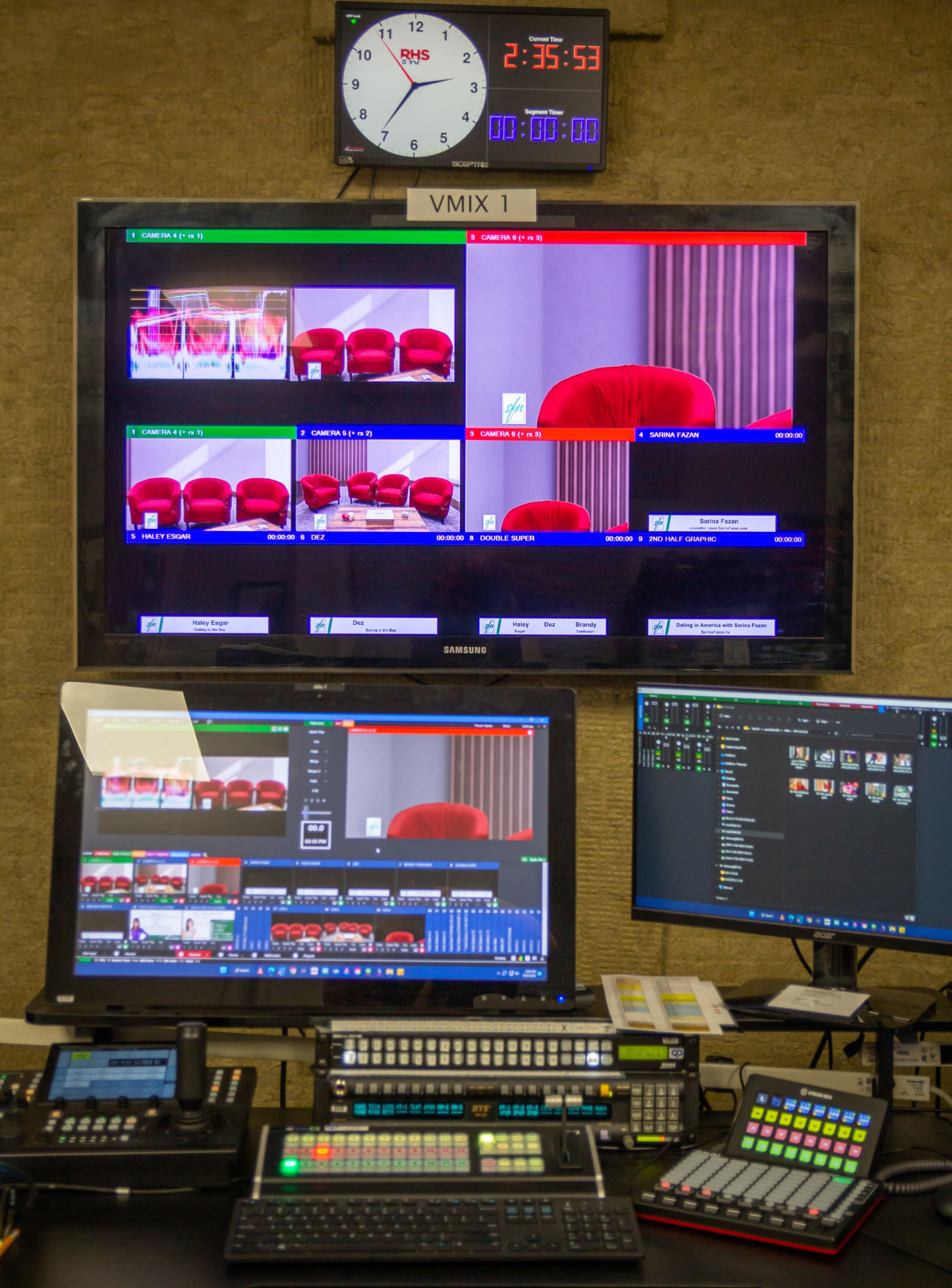 A broadcast control room with multiple screens displaying different camera feeds and a clock on the wall.