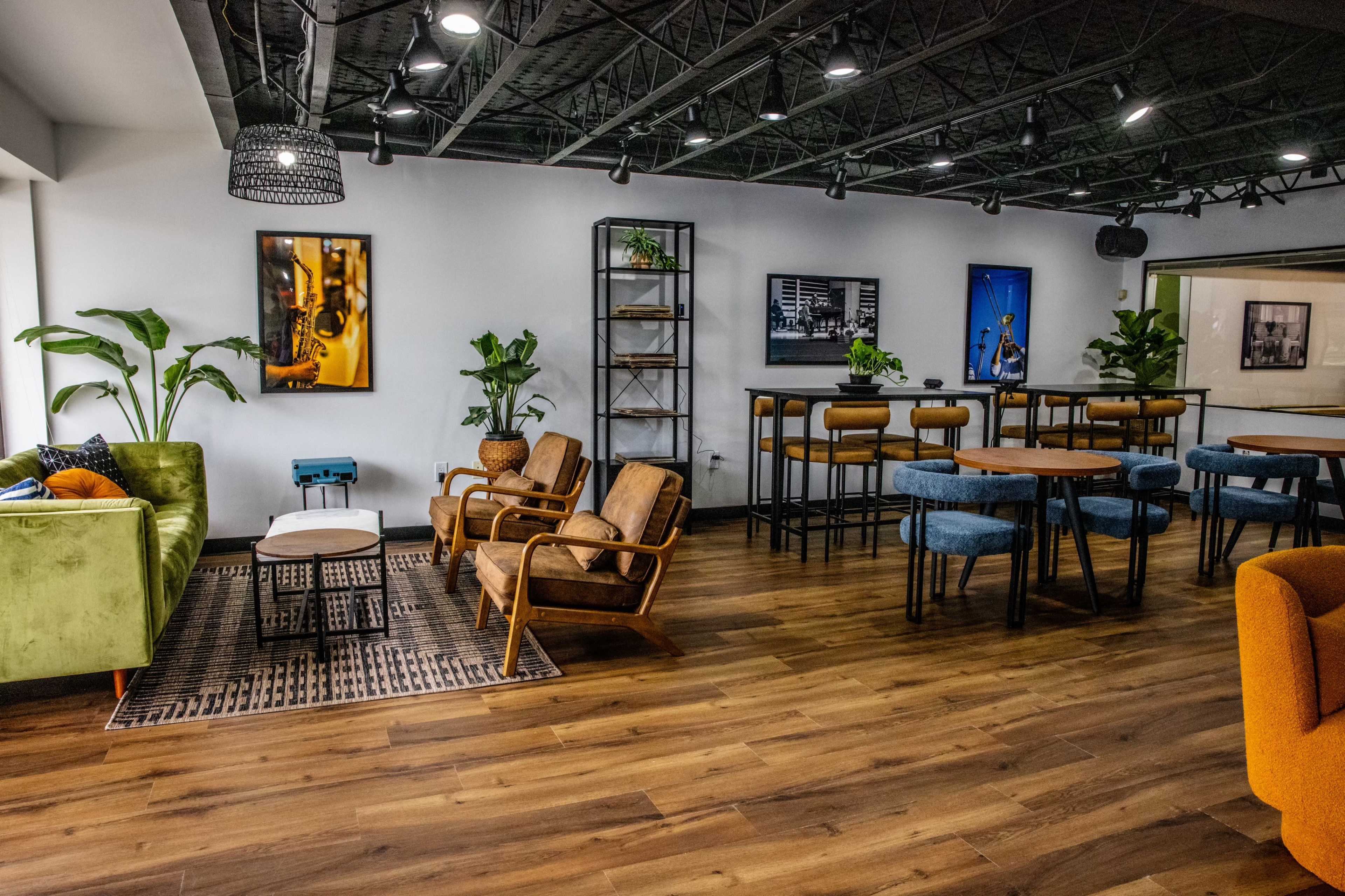 A modern interior space featuring various seating arrangements, plants, and decorative artwork on the walls.