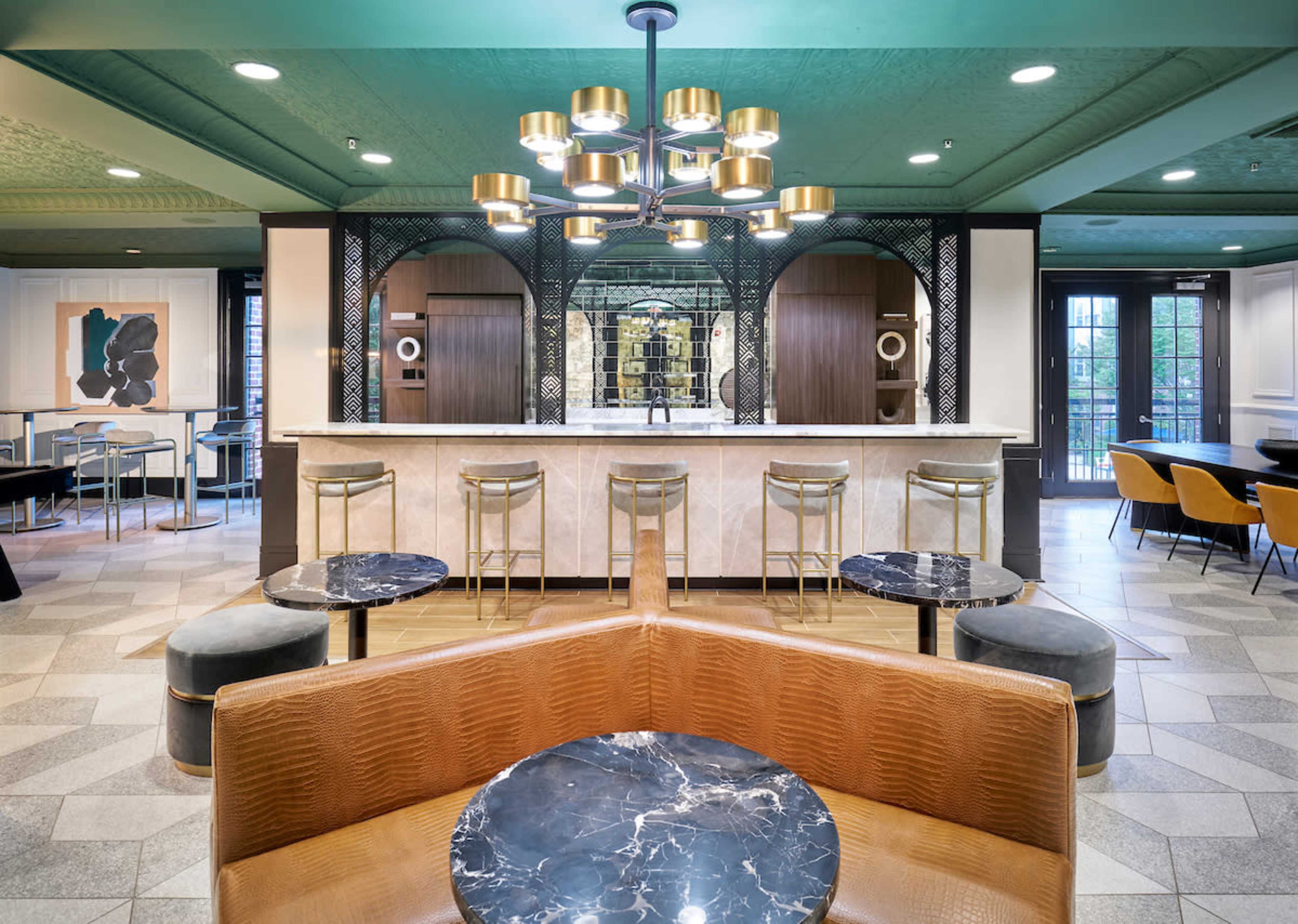 A modern interior of a café or lounge area featuring a marble bar, pendant lighting, and various seating arrangements.