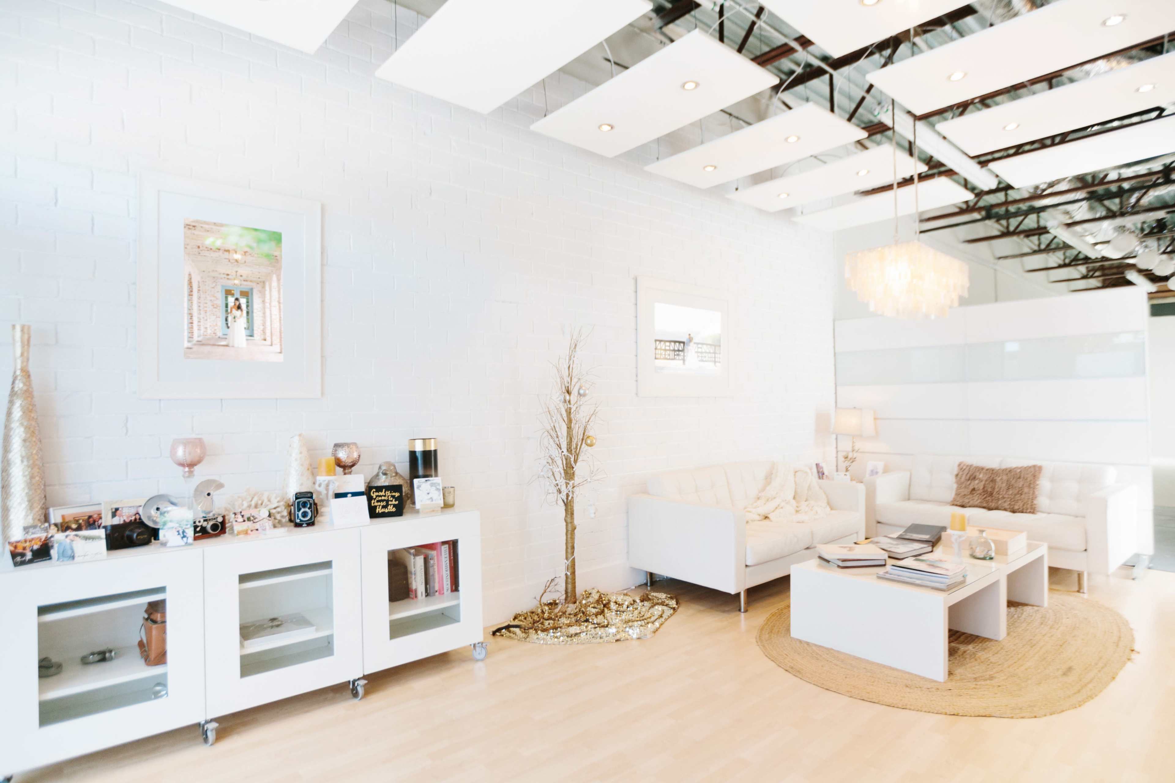 A modern, minimalist living space featuring white brick walls, light wood flooring, and a combination of white furniture and decorative elements.