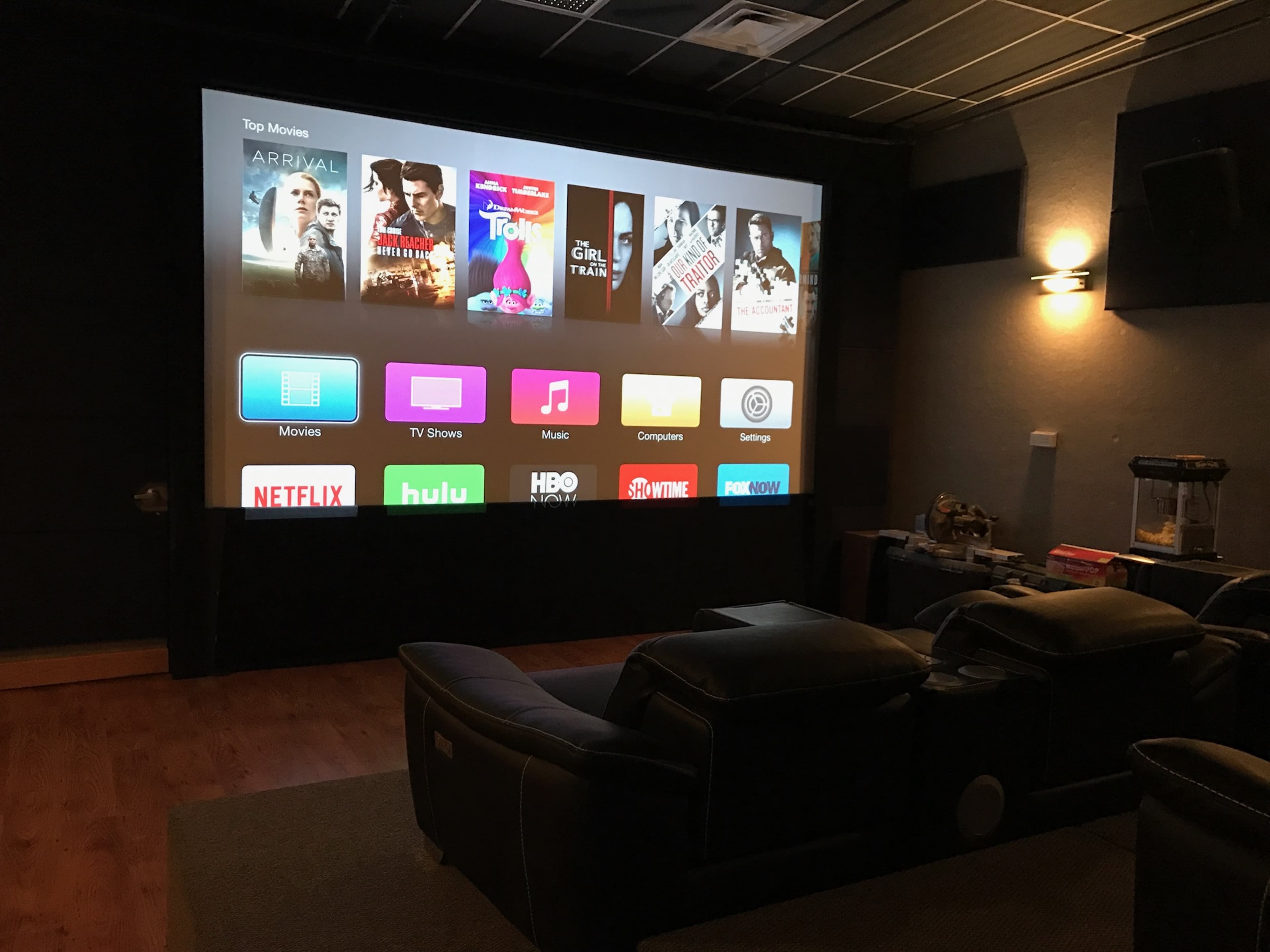 A home theater displays a large screen with streaming options for movies, TV shows, and music.