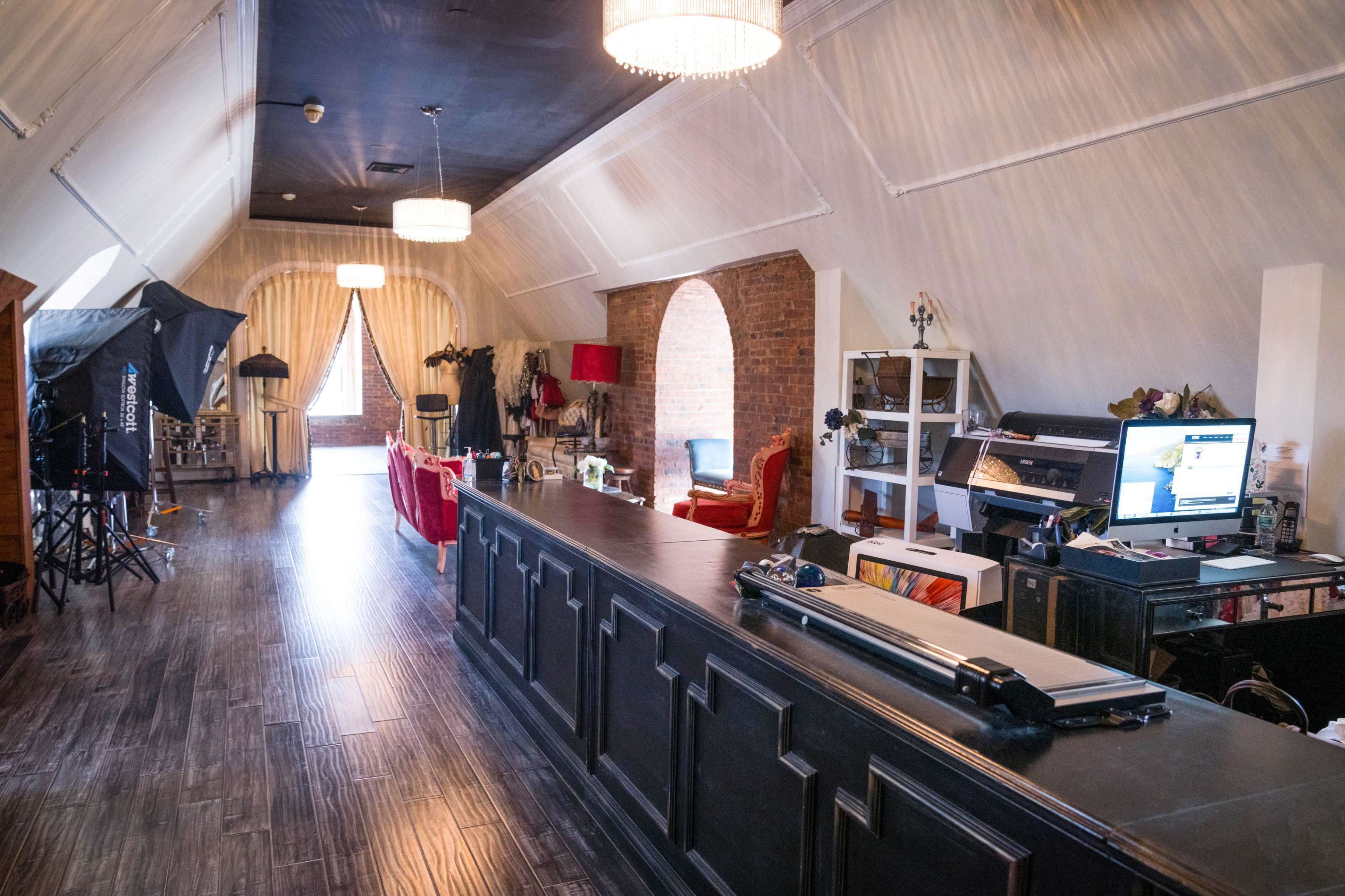 A spacious interior with a long dark counter, several chairs, and a mix of photography equipment and decorative elements along the walls.