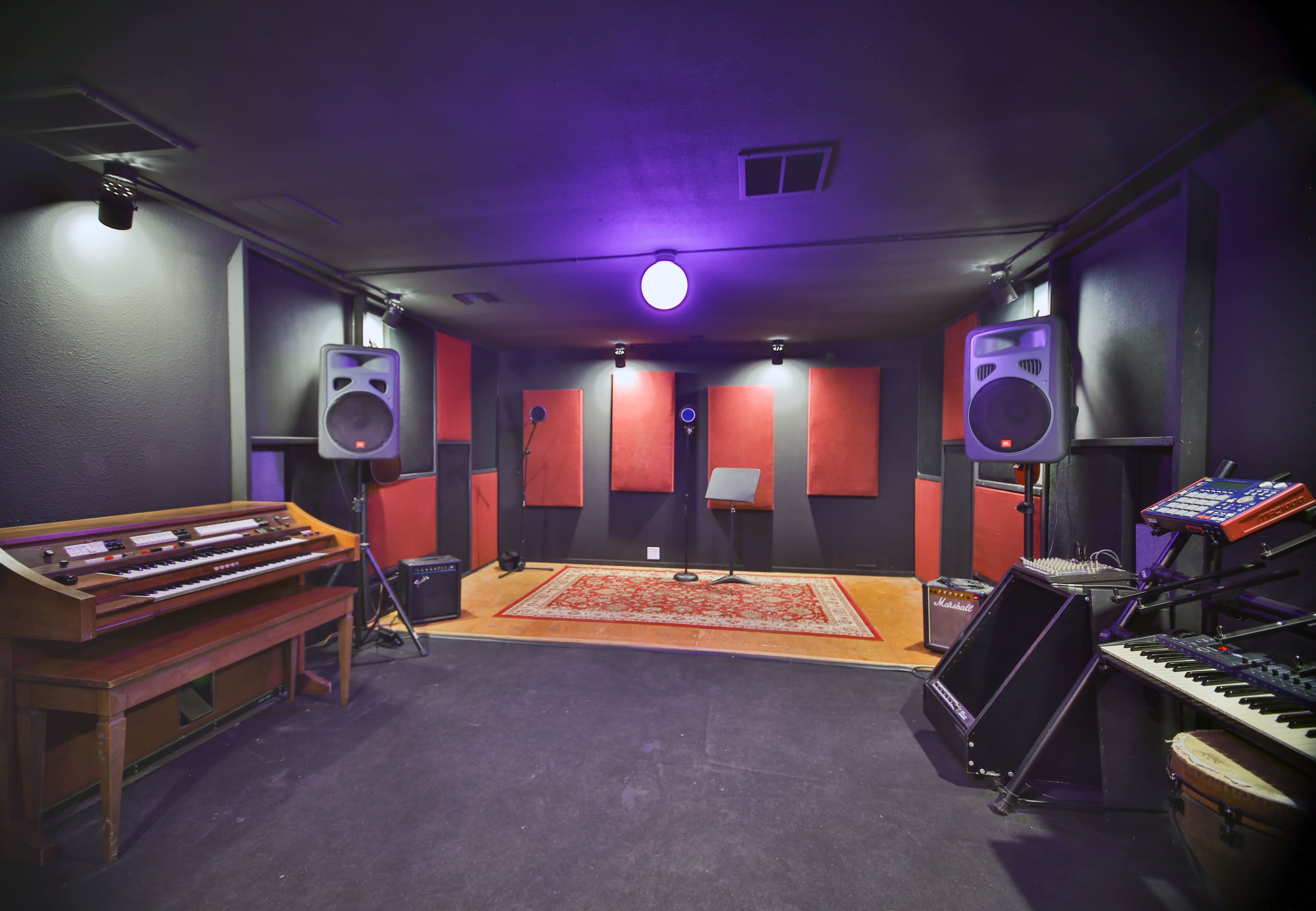 A music recording studio featuring audio equipment, microphones on stands, and a vintage organ.