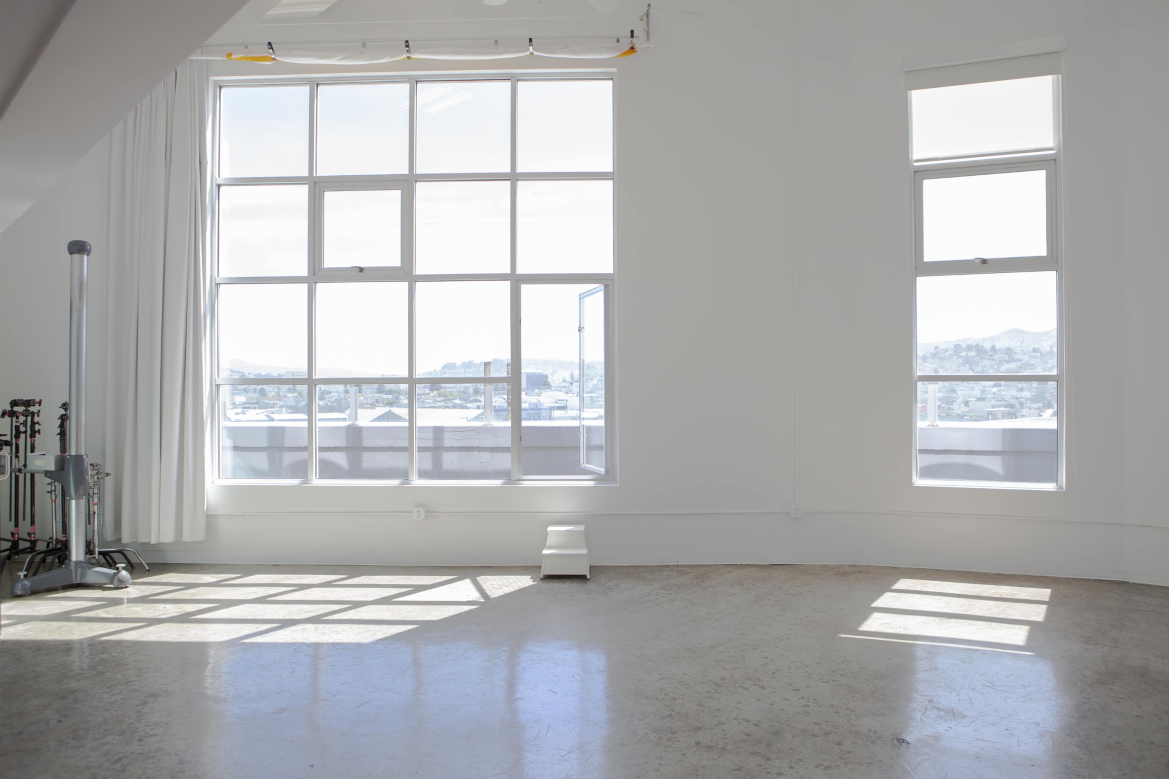 A bright, spacious room with large windows allows natural light to fill the space, highlighting the polished floor and minimalist decor.