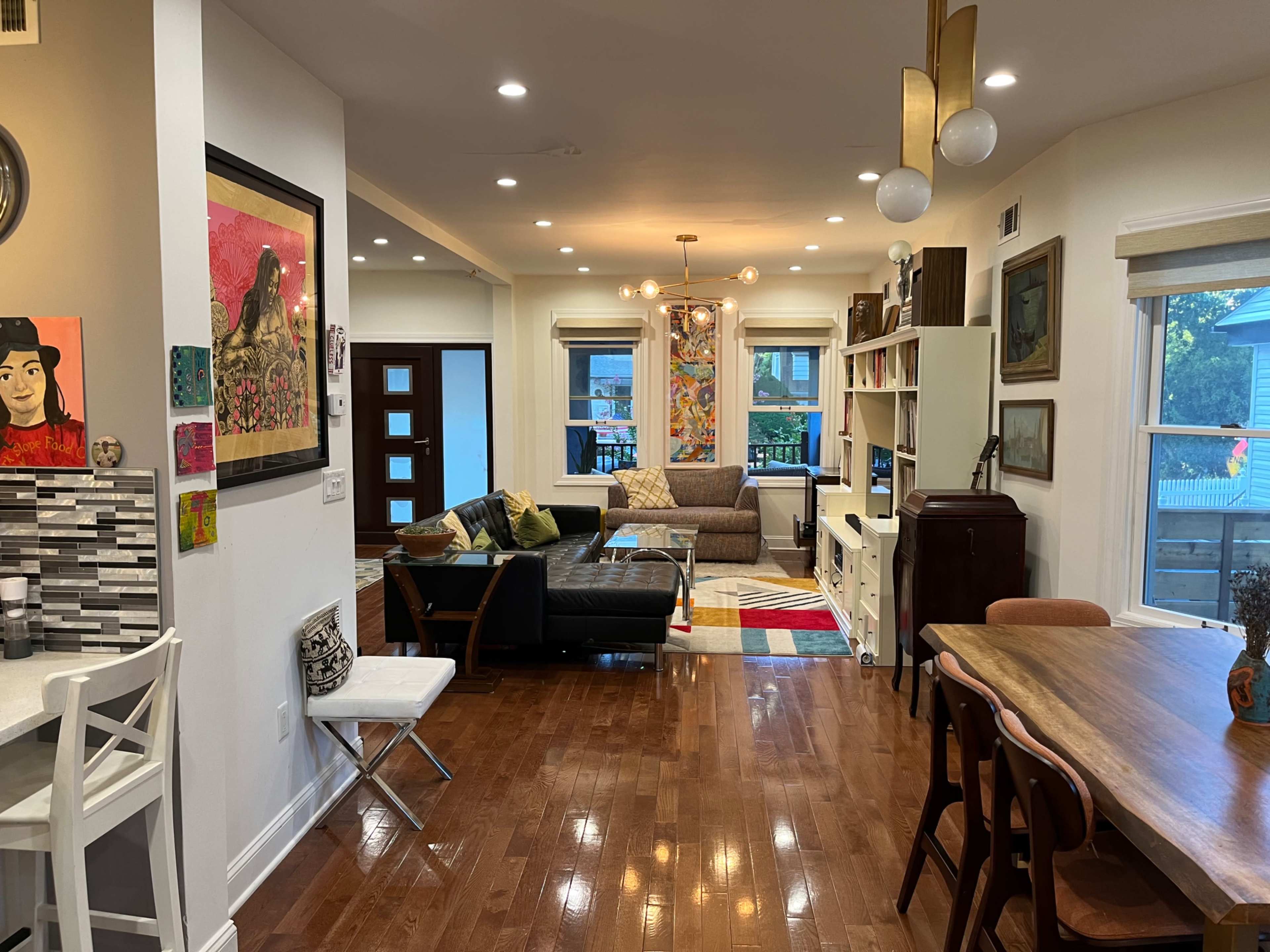 A modern living space featuring a mix of furniture, including a dining area, a seating area with a sectional couch, and decorative artwork on the walls.