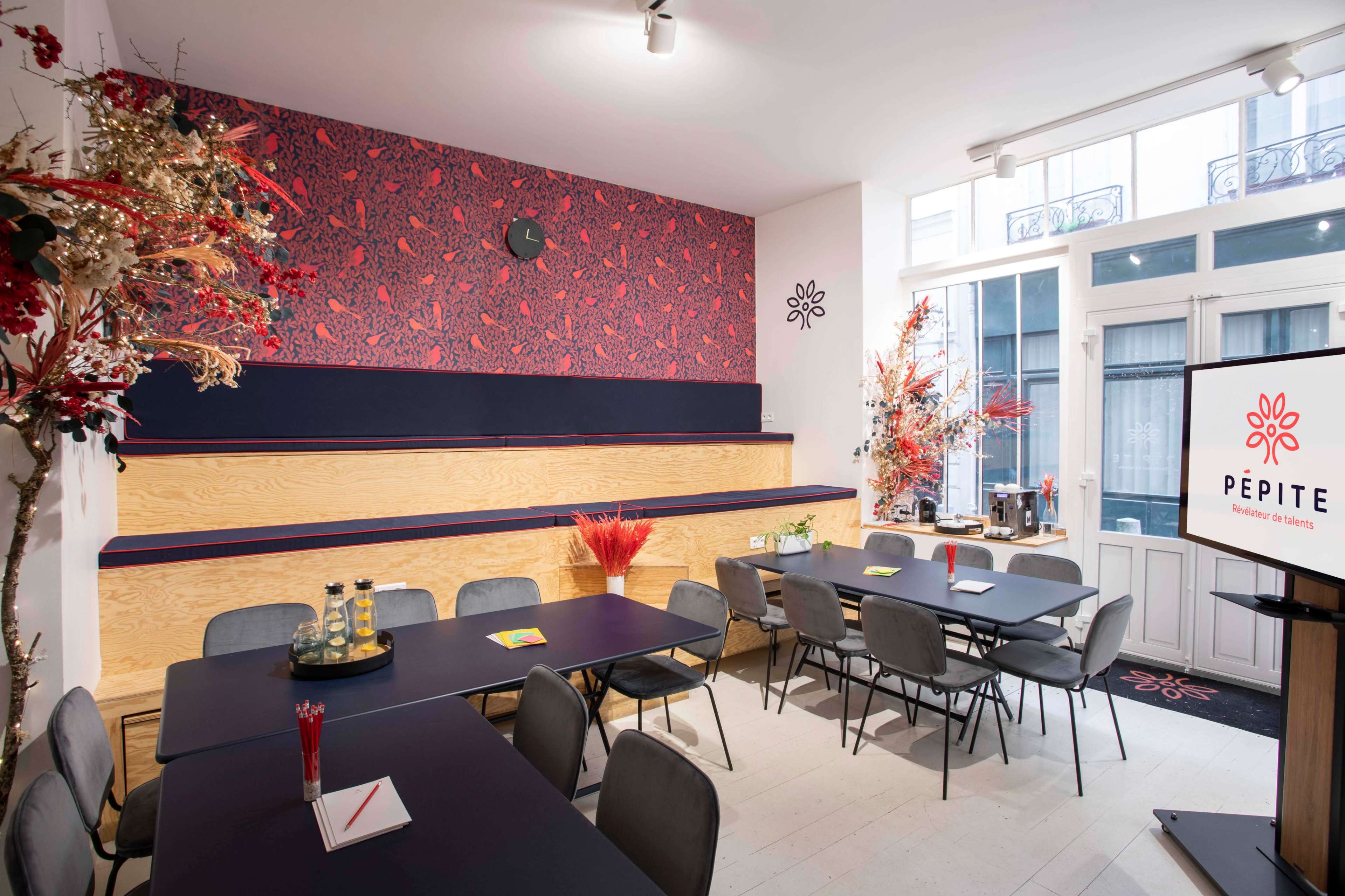 A modern meeting room with wooden and dark furniture, decorated with a patterned wallpaper and vibrant floral arrangements.
