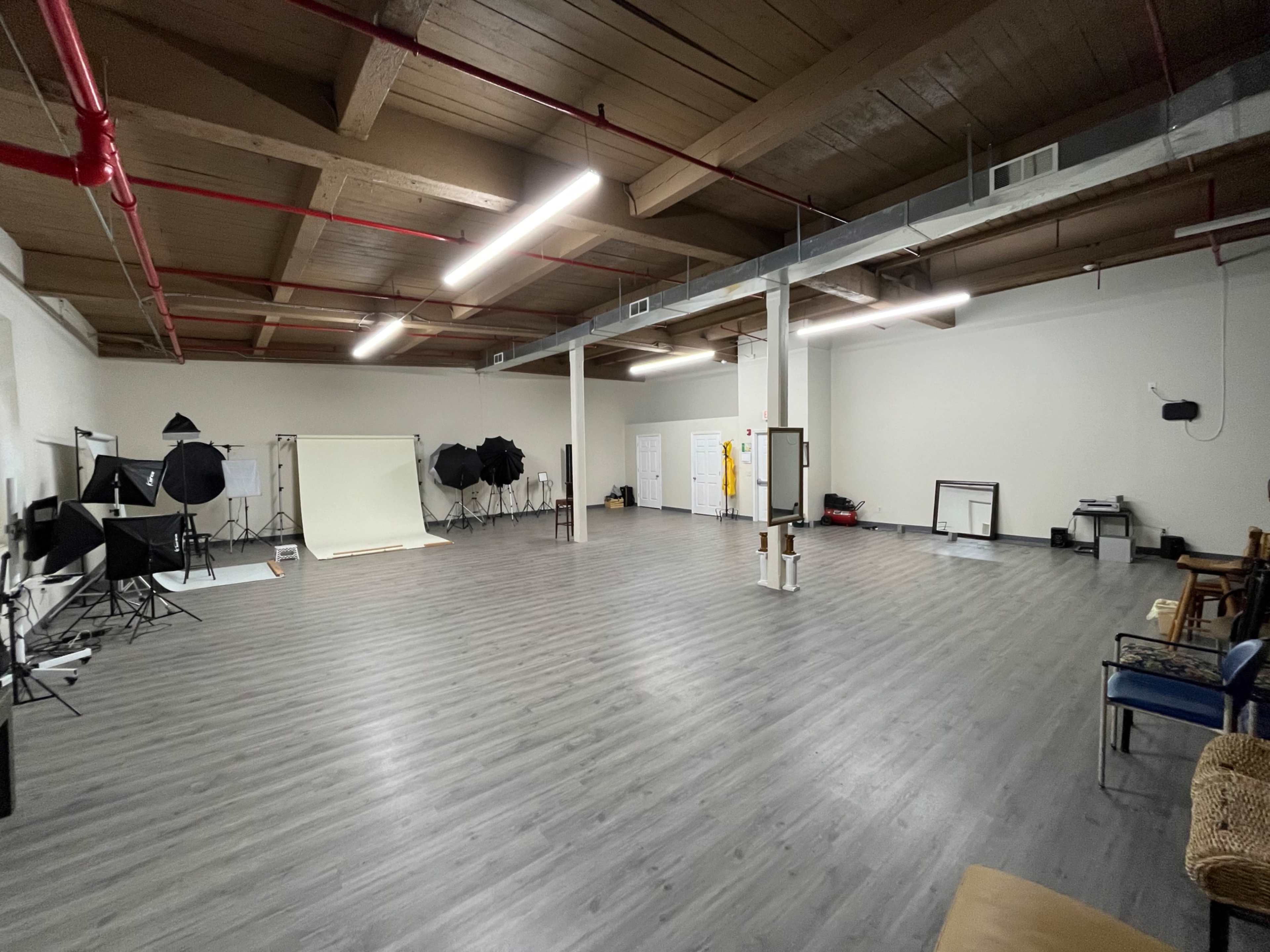 The image shows a spacious photography studio with various lighting equipment and backdrops set up along the walls.