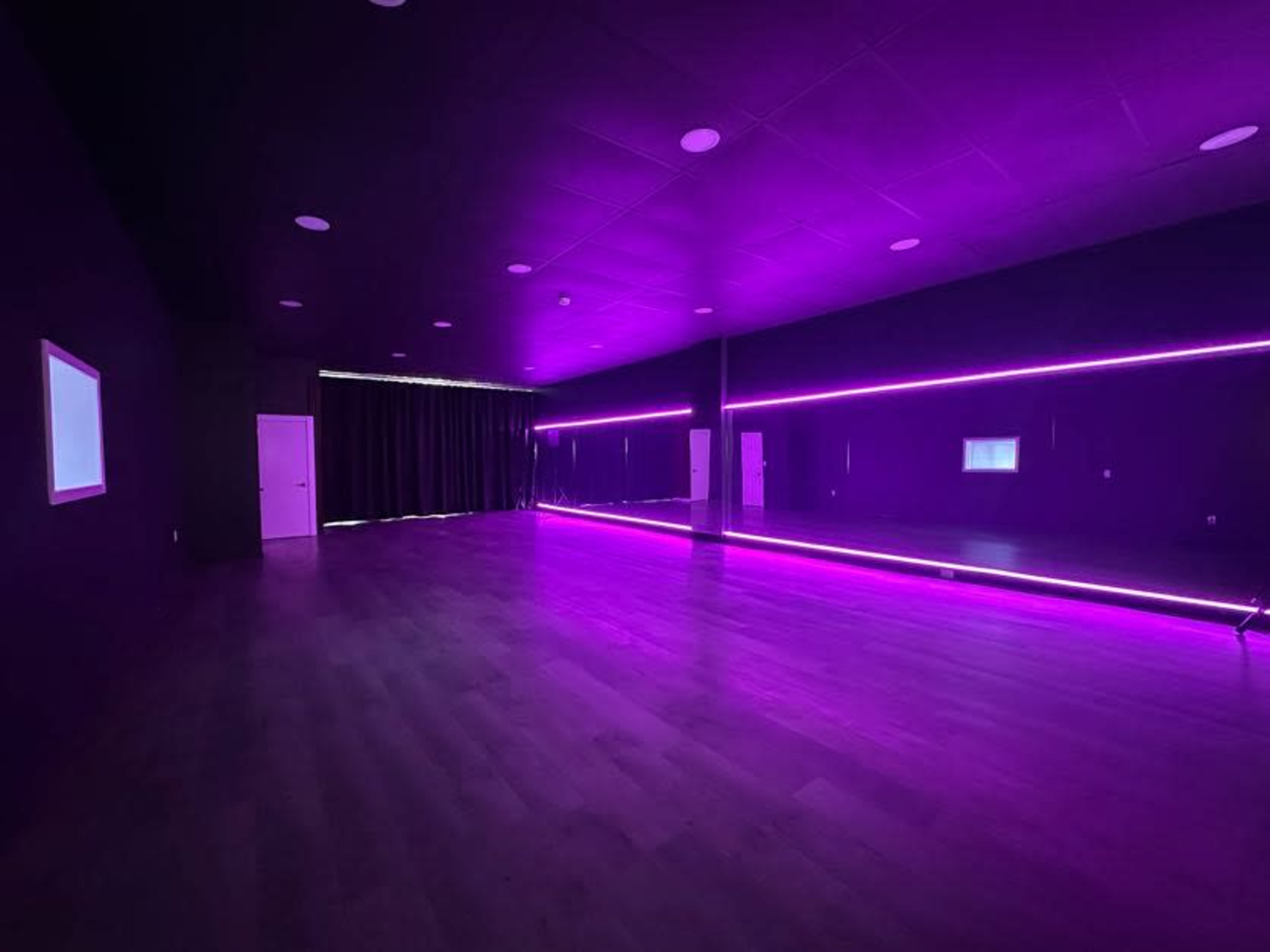 The image shows a dimly lit studio with purple LED lighting and a large mirror along one wall.
