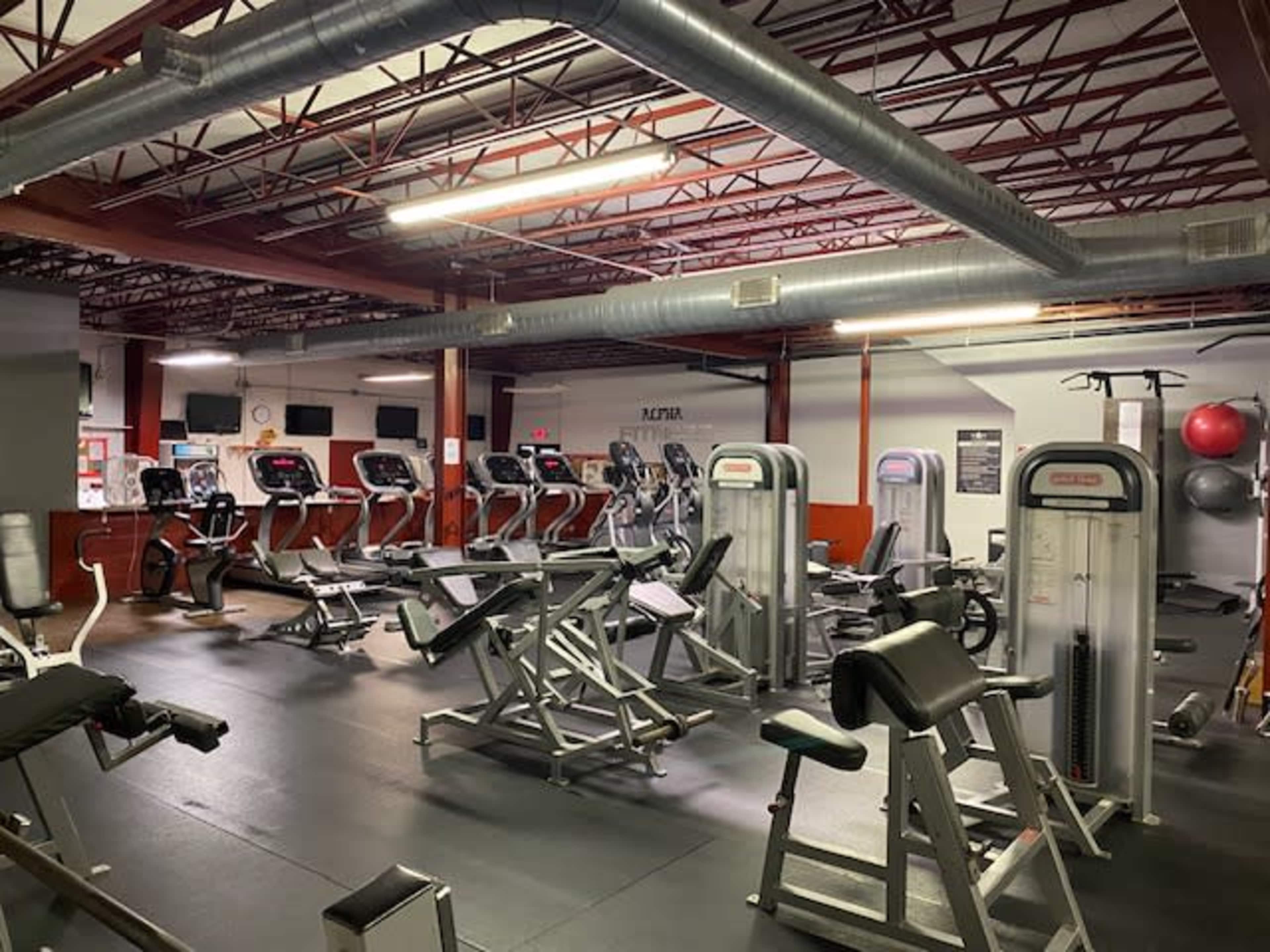 An empty gym with various exercise machines and equipment arranged throughout the space.