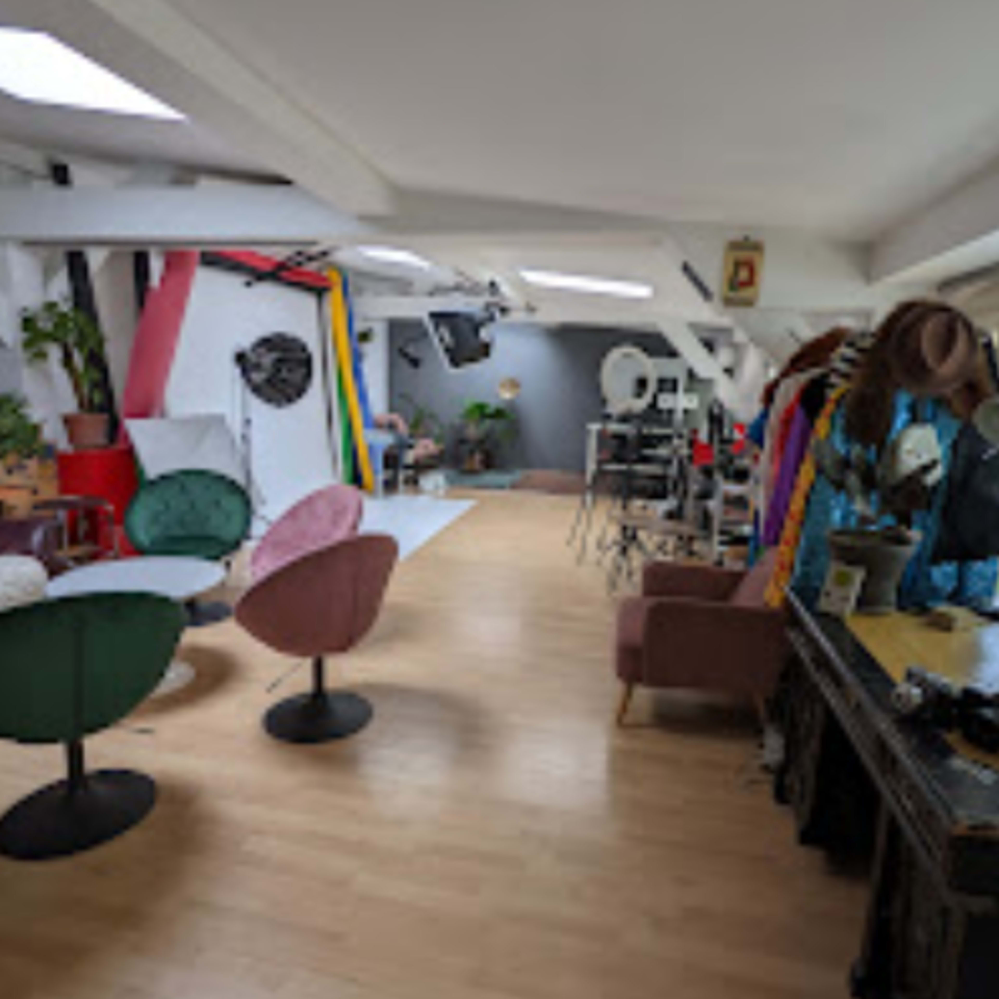 A spacious studio with various seating areas, colorful backdrops, and photography equipment.