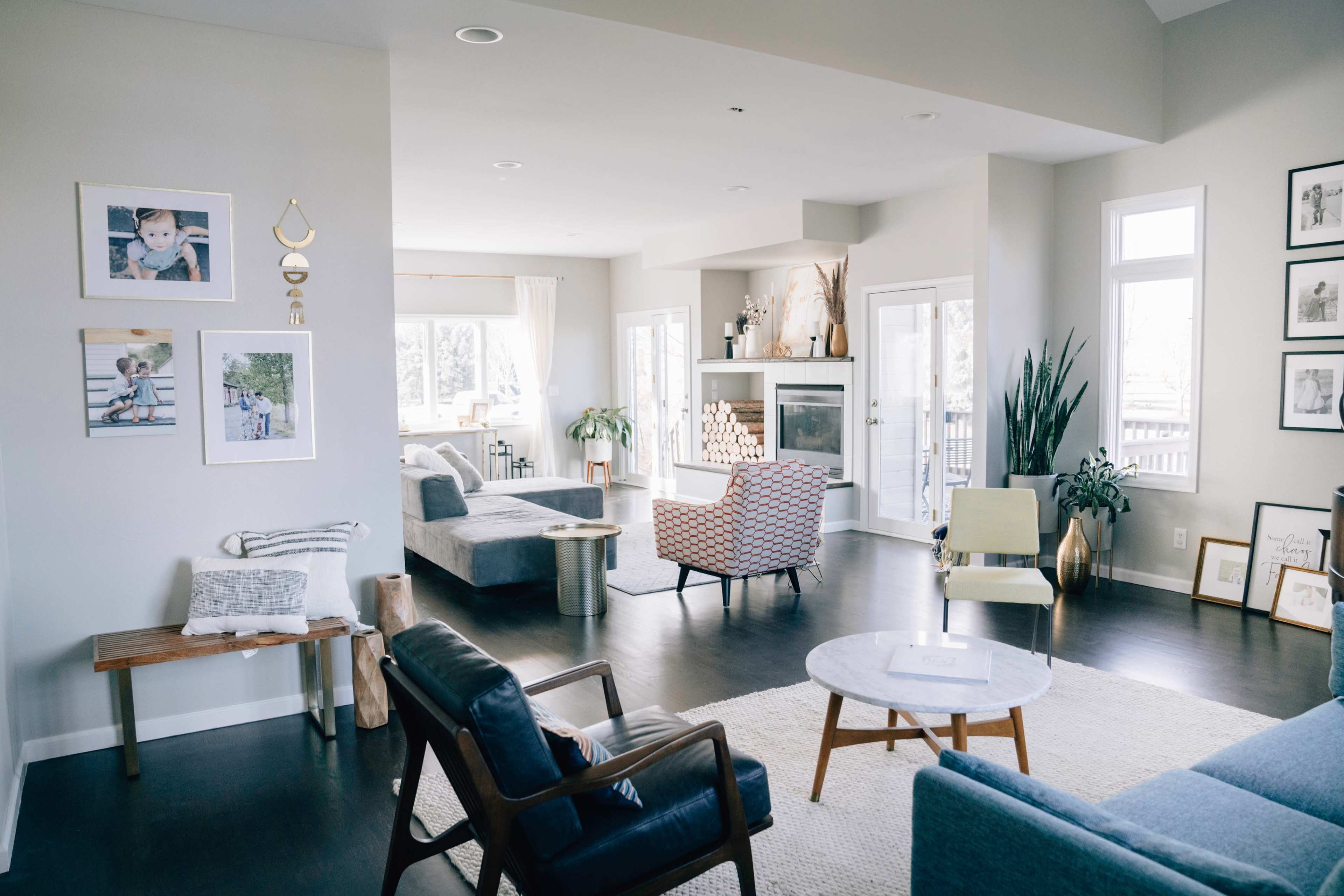 A spacious, modern living room features a mix of seating, a fireplace, and large windows allowing natural light.