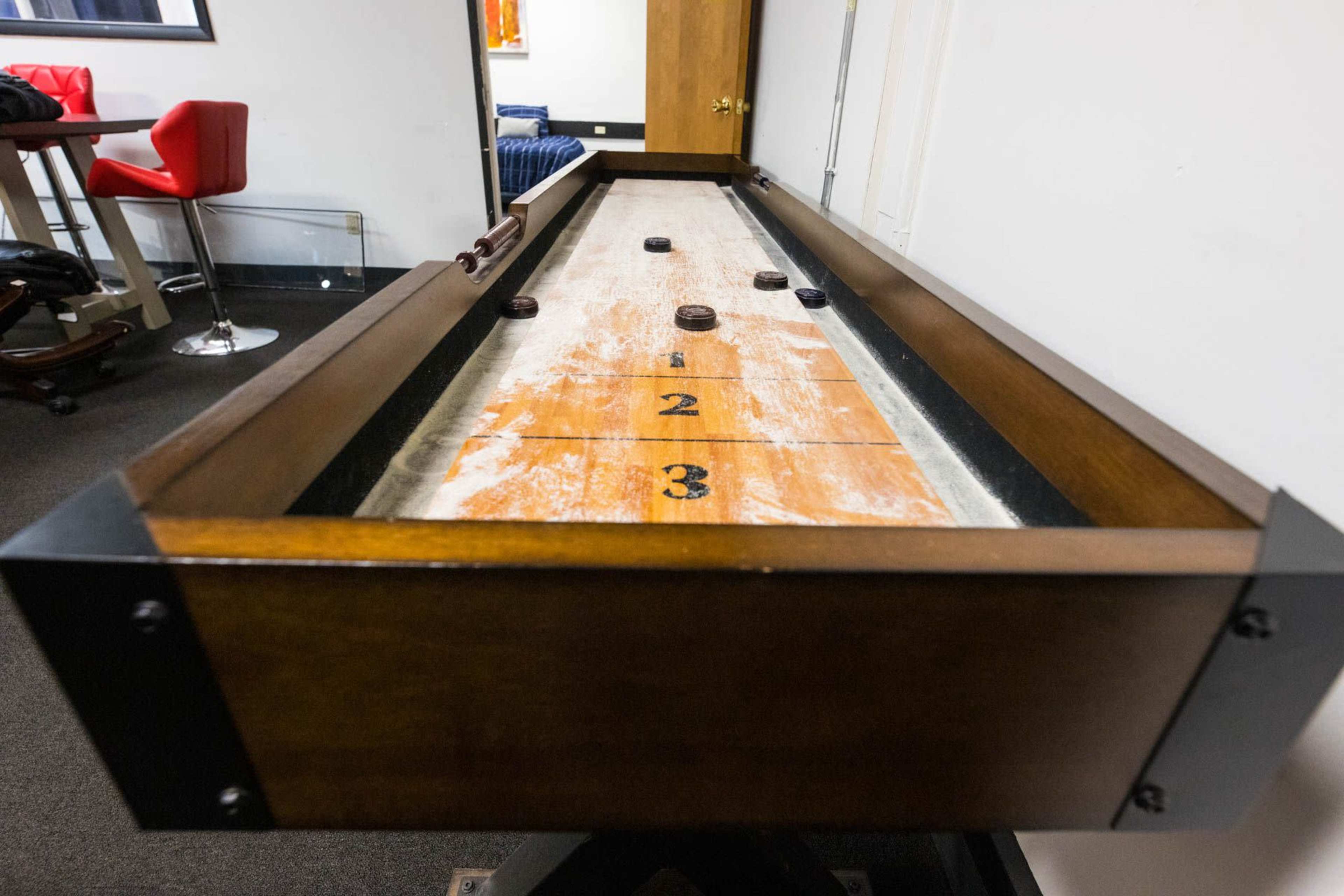 A wooden shuffleboard table with pucks positioned on the playing surface, marked with numbers indicating scoring zones.