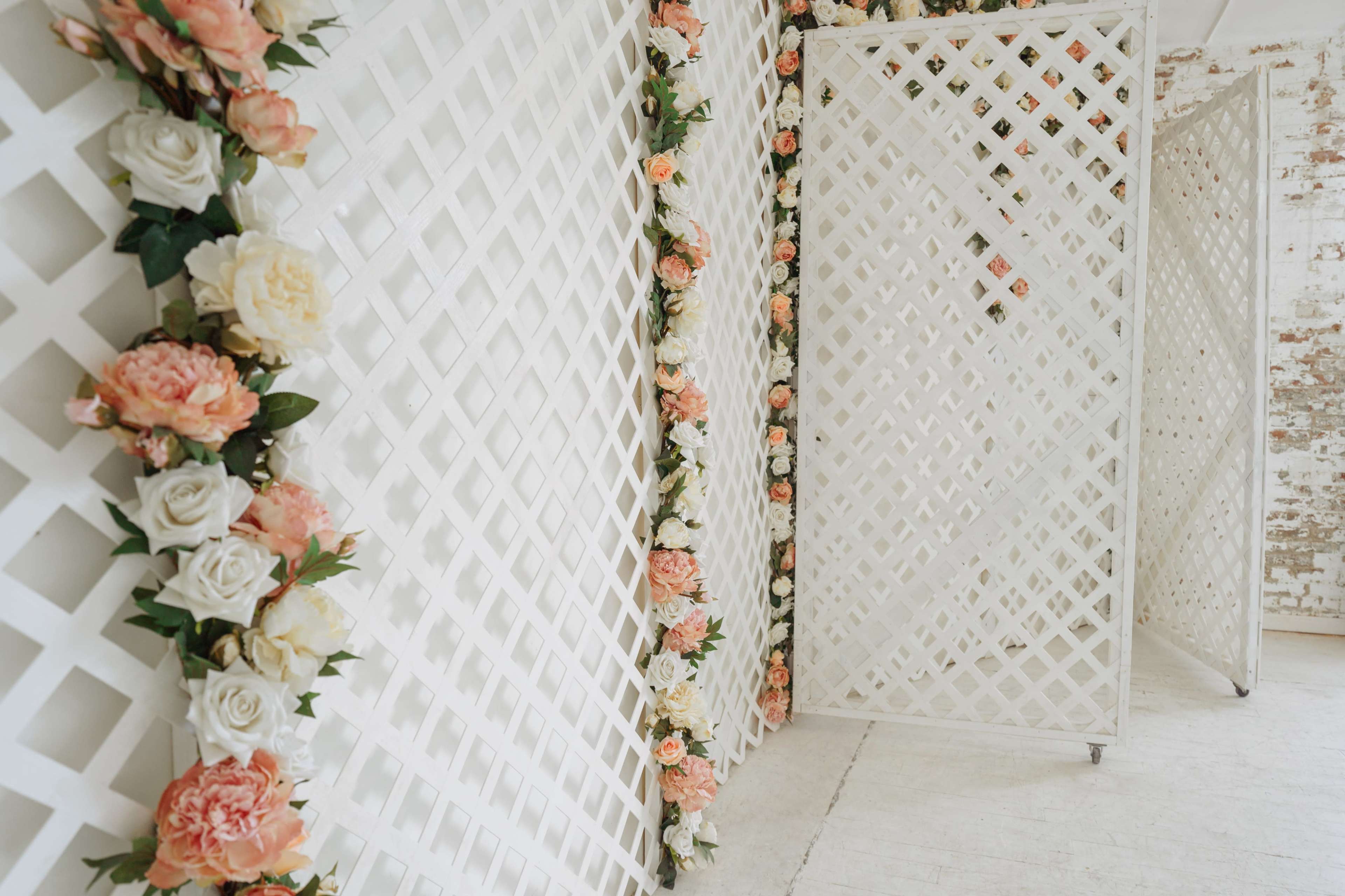 A series of white lattice panels decorated with artificial flowers, arranged in a bright indoor space.