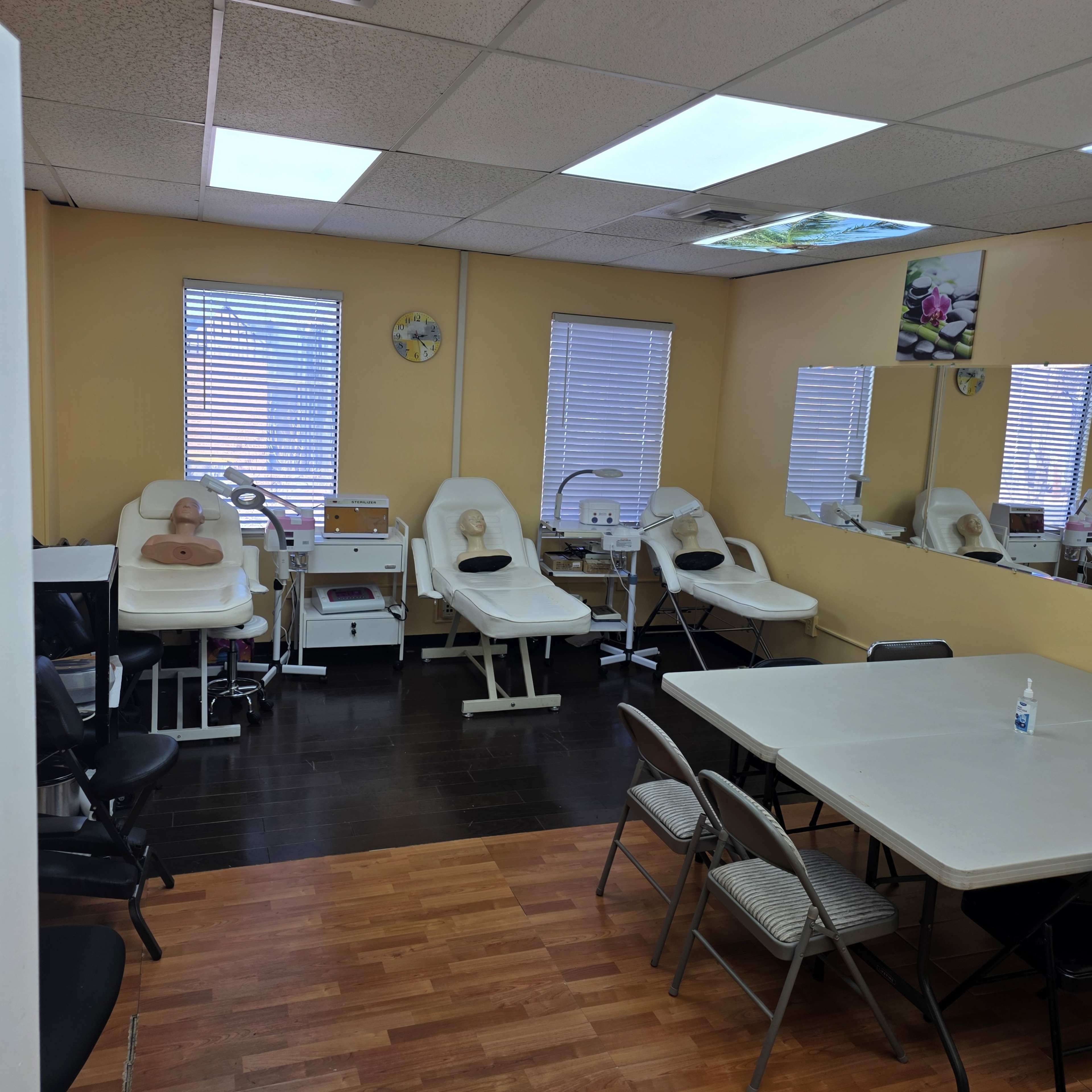 The image shows a well-lit training room equipped with multiple treatment chairs, a table with folding chairs, and a mirror along one wall.
