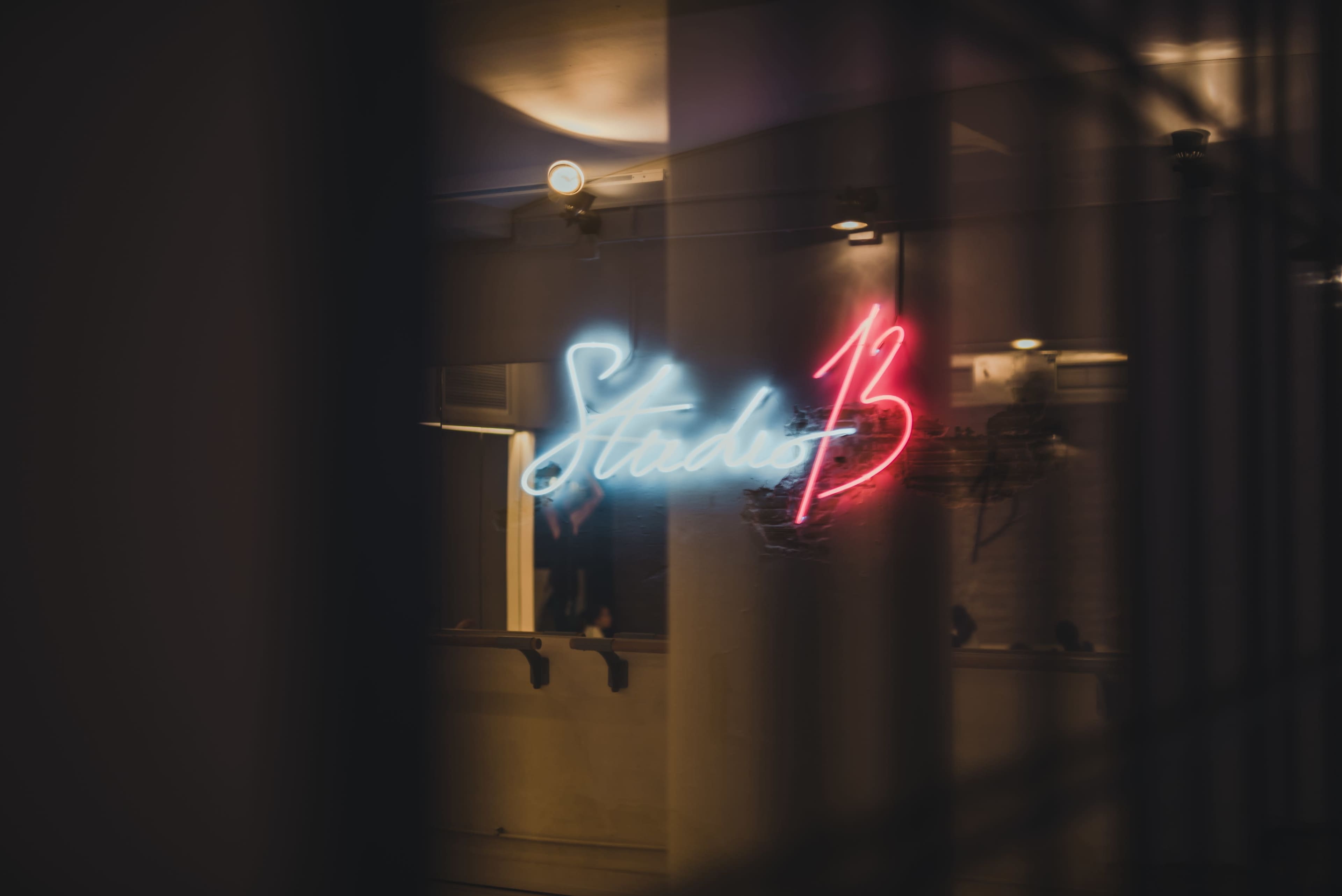 A neon sign reading "Studio 13" glows in blue and red on a wall, reflecting the ambiance of the room behind it.