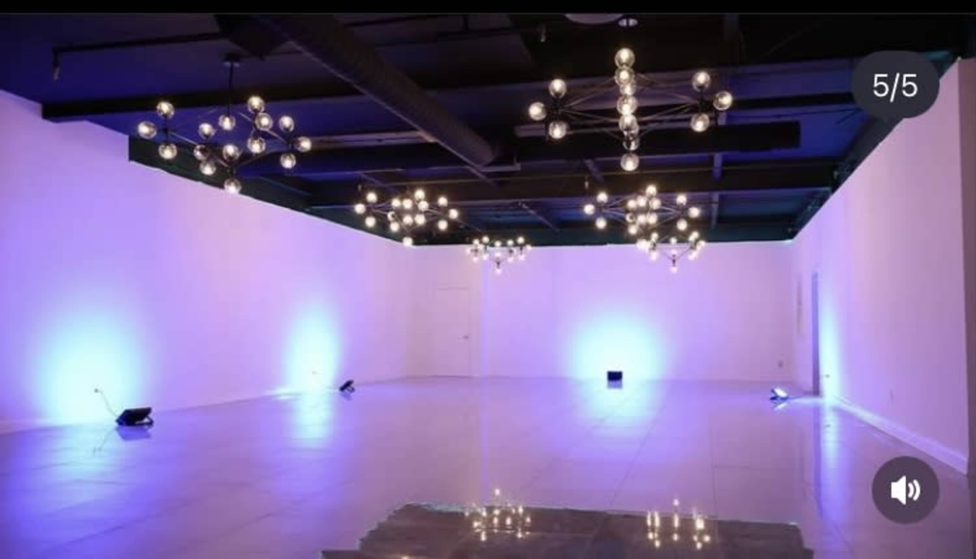 The image shows a spacious, empty room illuminated by various modern light fixtures and blue accent lights.