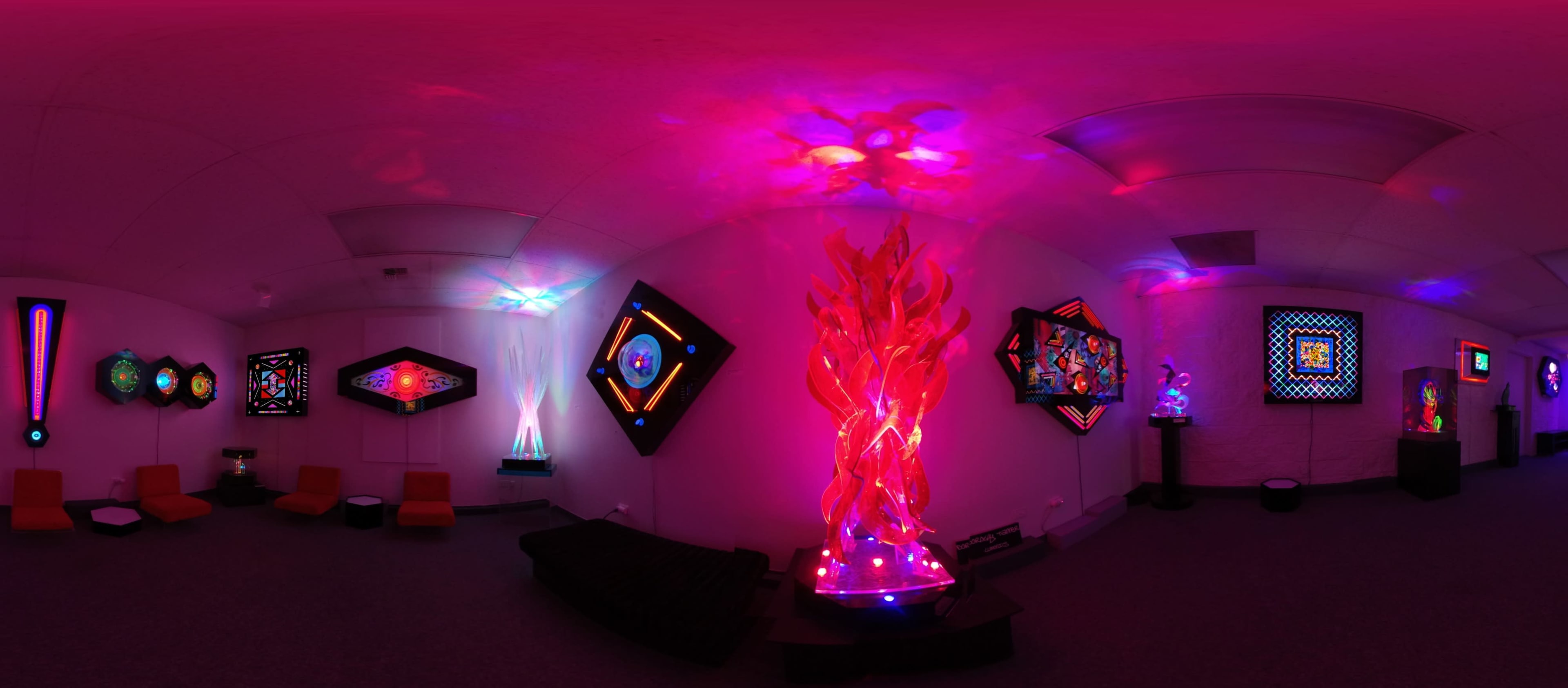 A vibrant art installation featuring colorful illuminated sculptures and wall art in a dimly lit room.