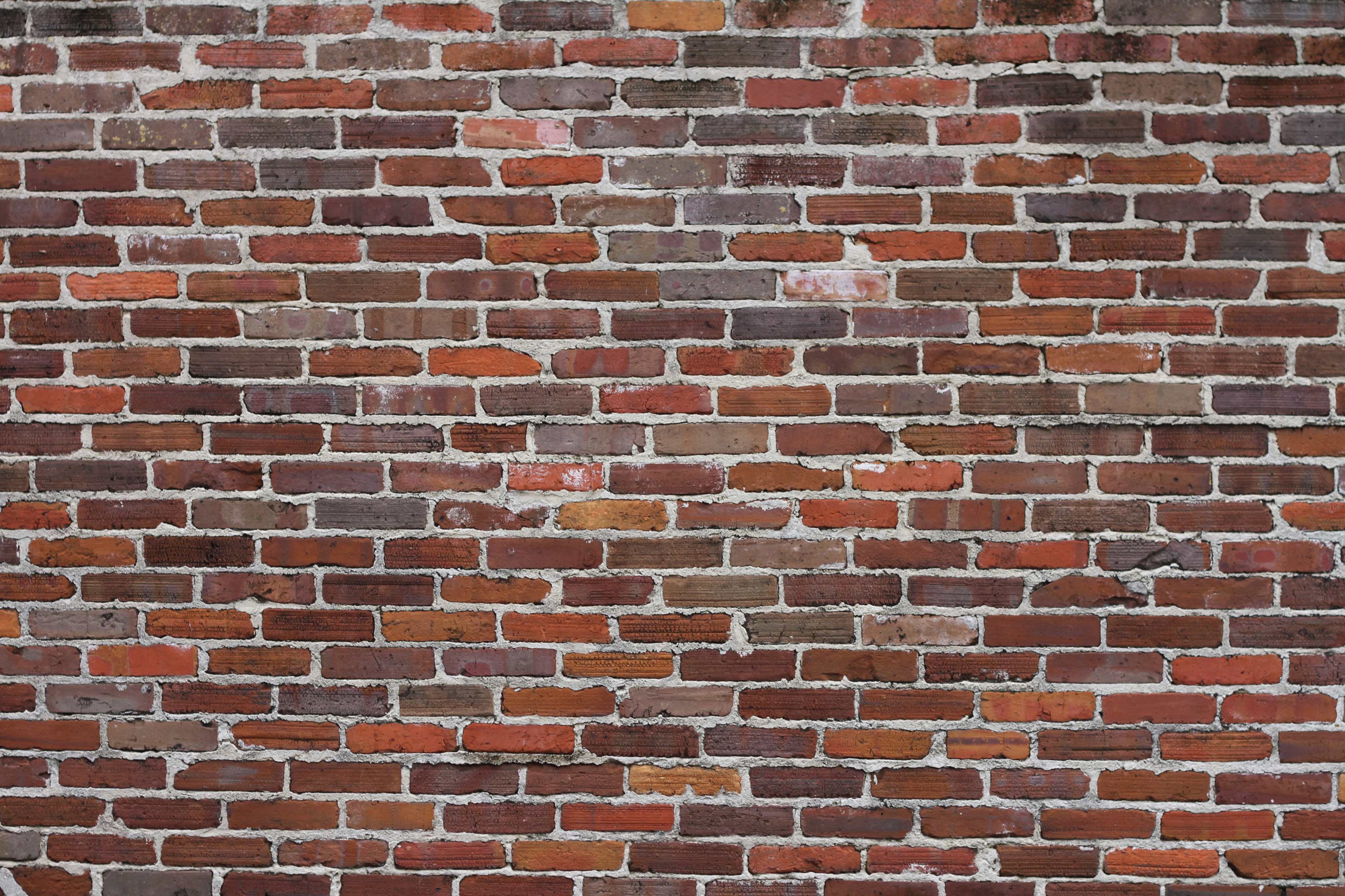 A close-up view of a textured brick wall with a mixture of red and brown bricks.