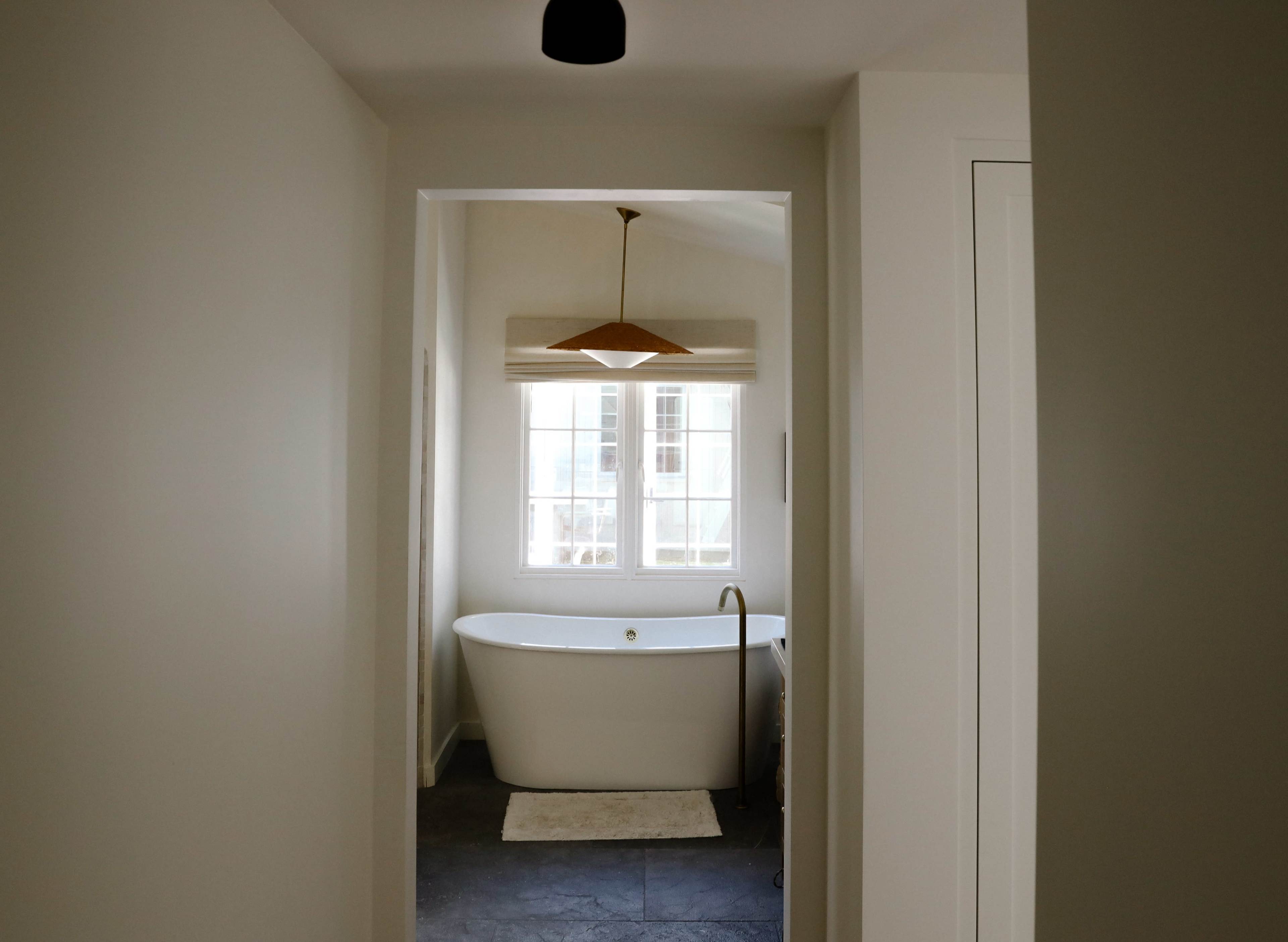 A view of a bathroom featuring a freestanding bathtub and a window with natural light.